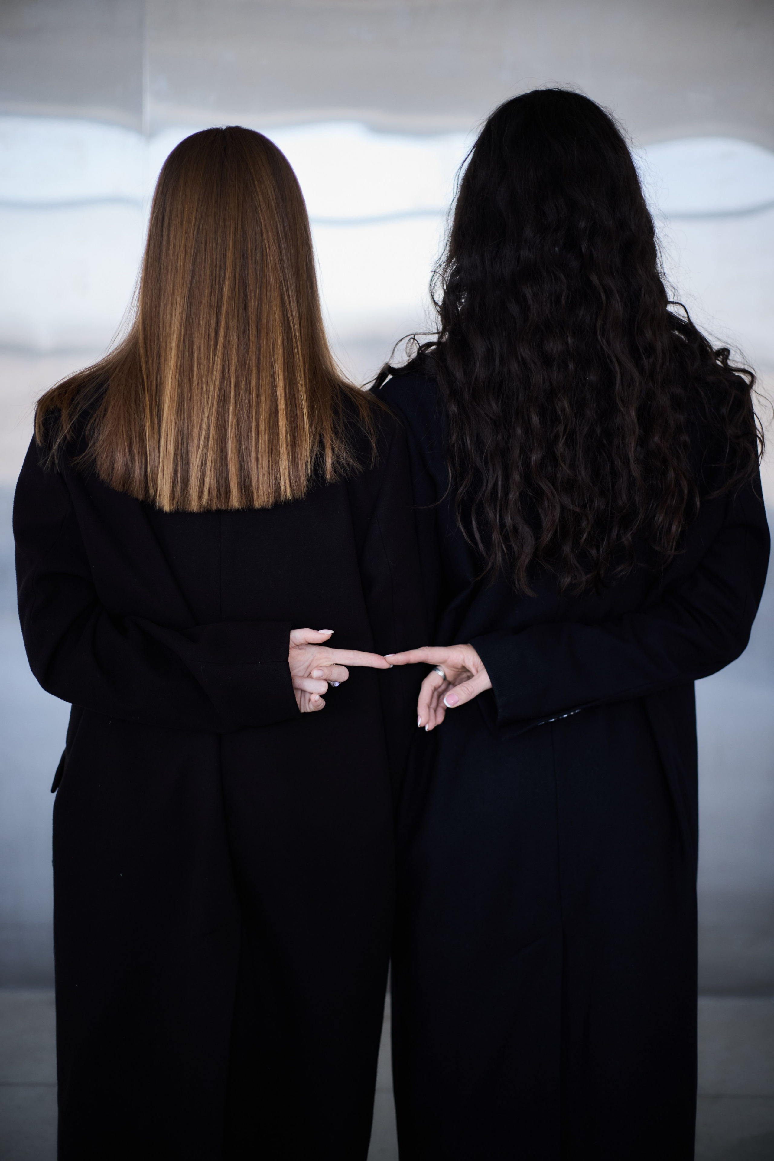 Две девушки на фоне металлической стены, стоят спиной, взявшись за руки. Виктория Брызгалова и Анна Пижонкова