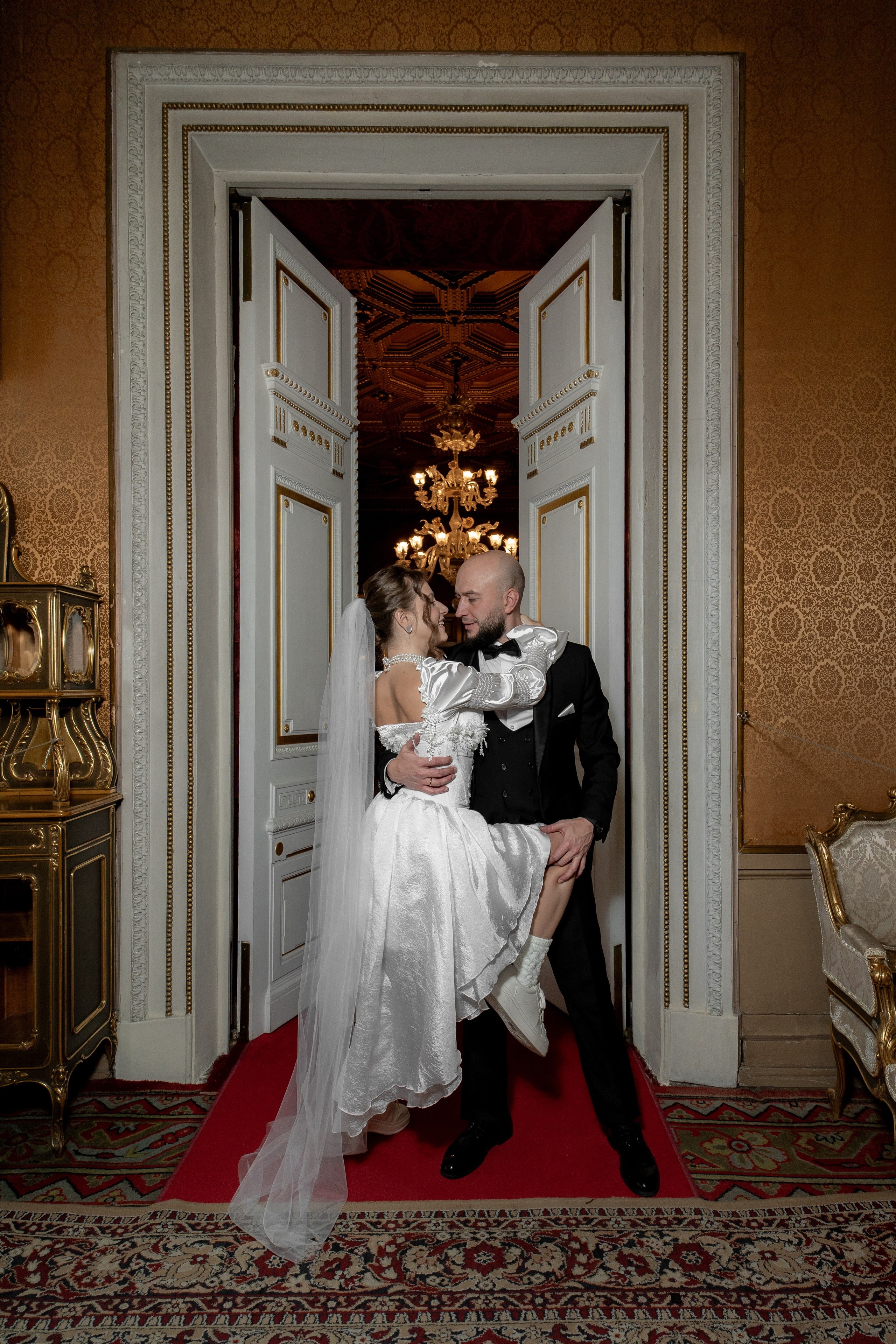 Невеста и жених красиво обнимаются во Дворце Великого Князя Владимира у красивых дверей
