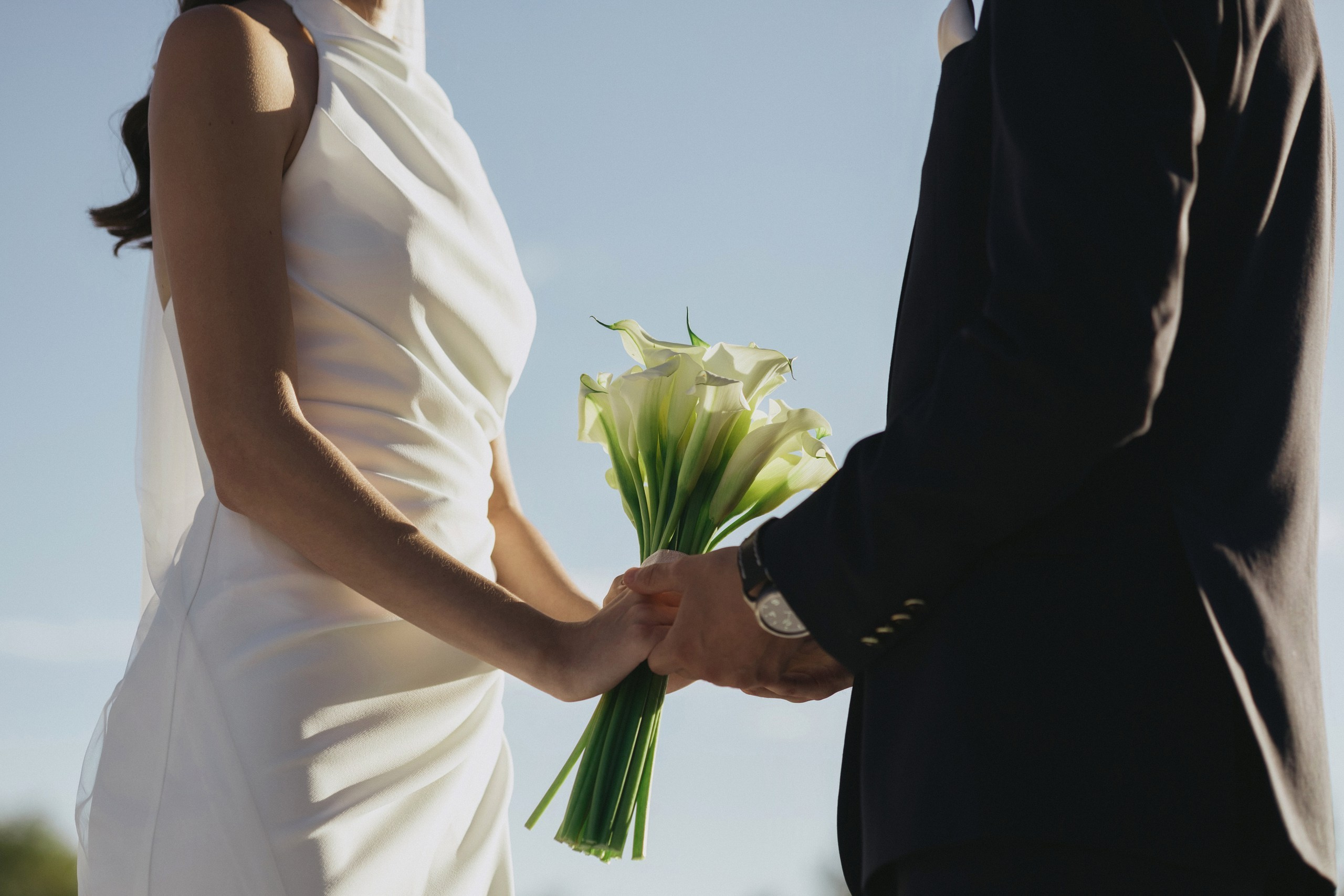 Жених Артём в тёмном костюме, обнимает невесту