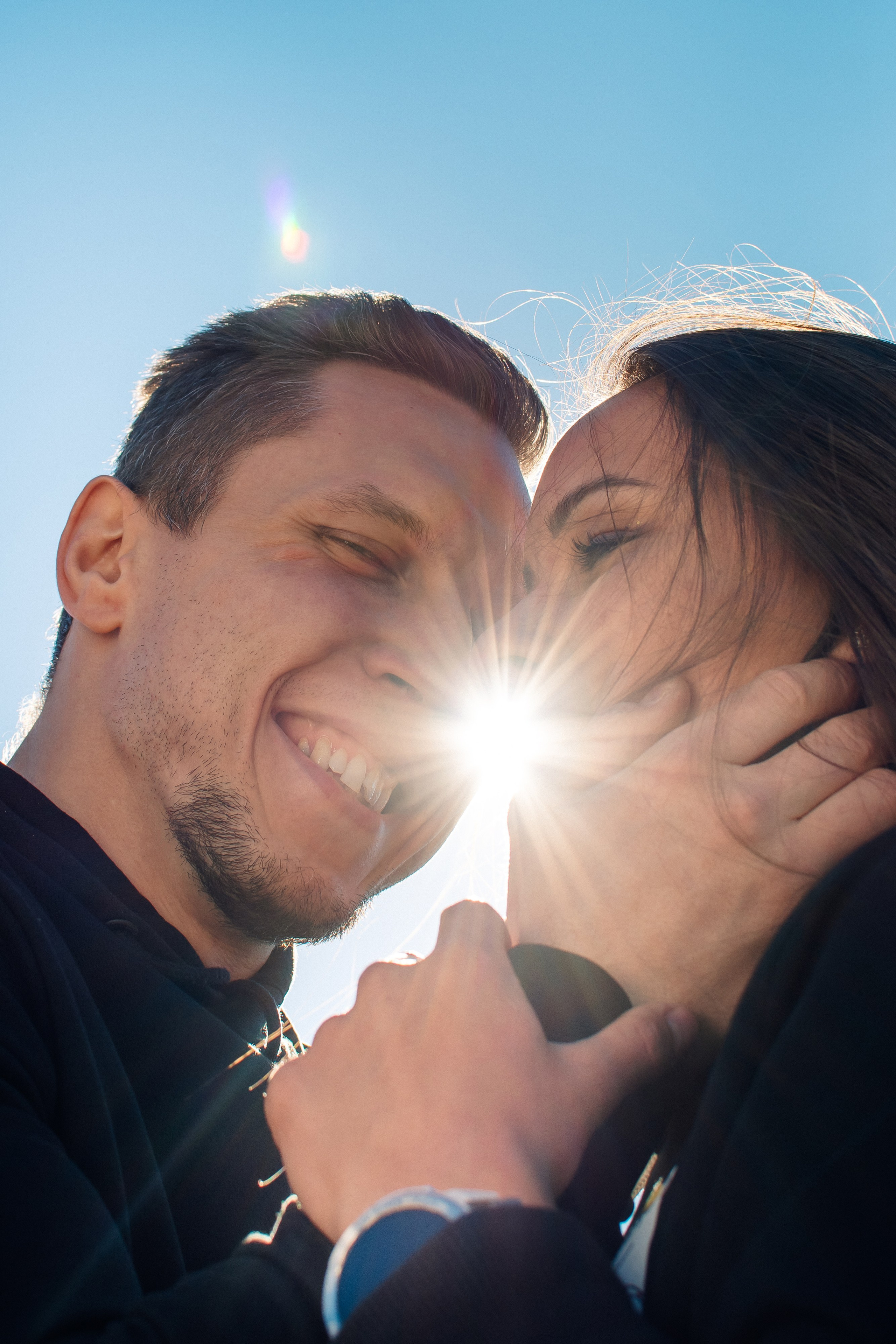 Парень приобнимает девушку на фоне солнца