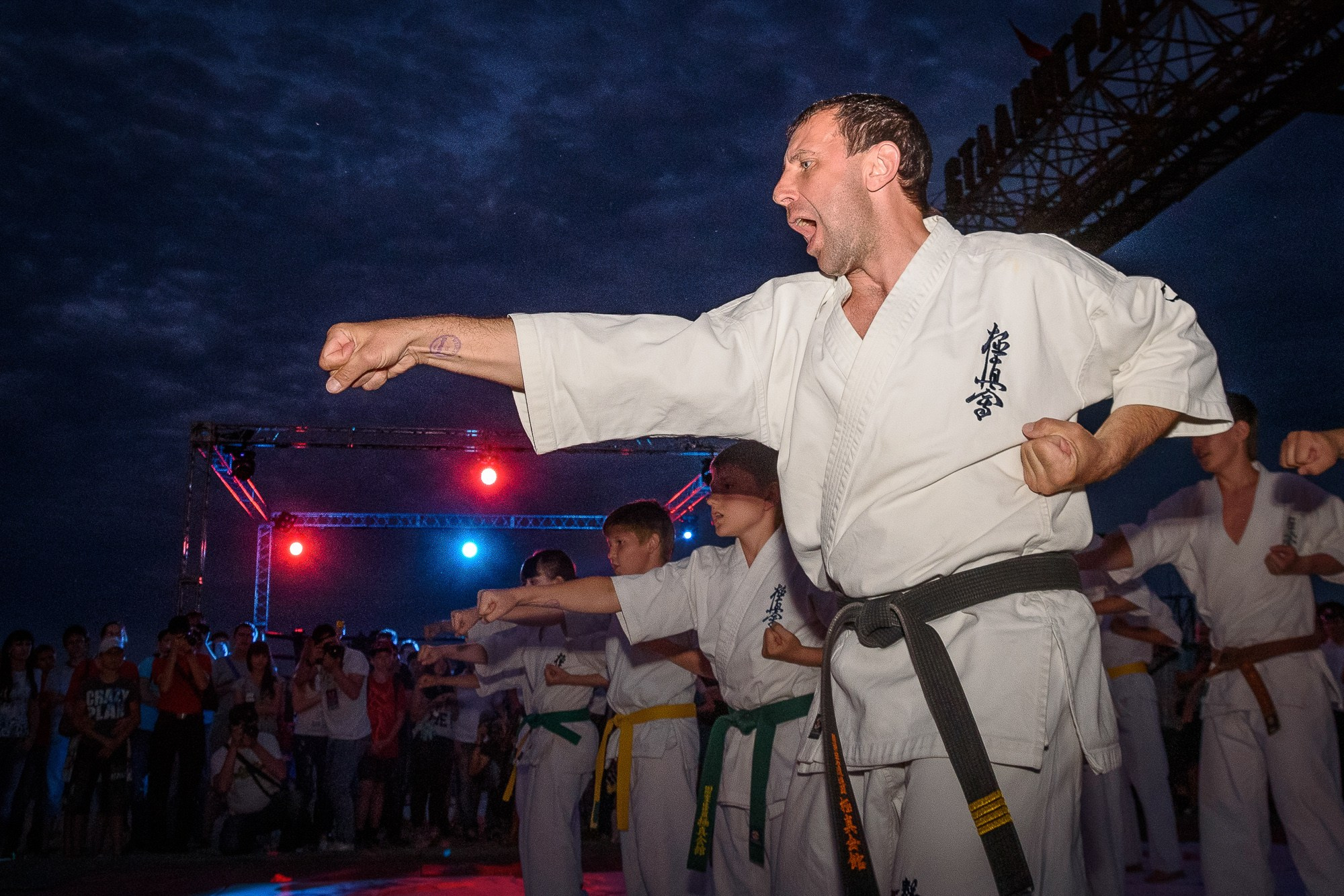 Мужчина в белом кимоно наносит удар рукой во время показательных выступлений