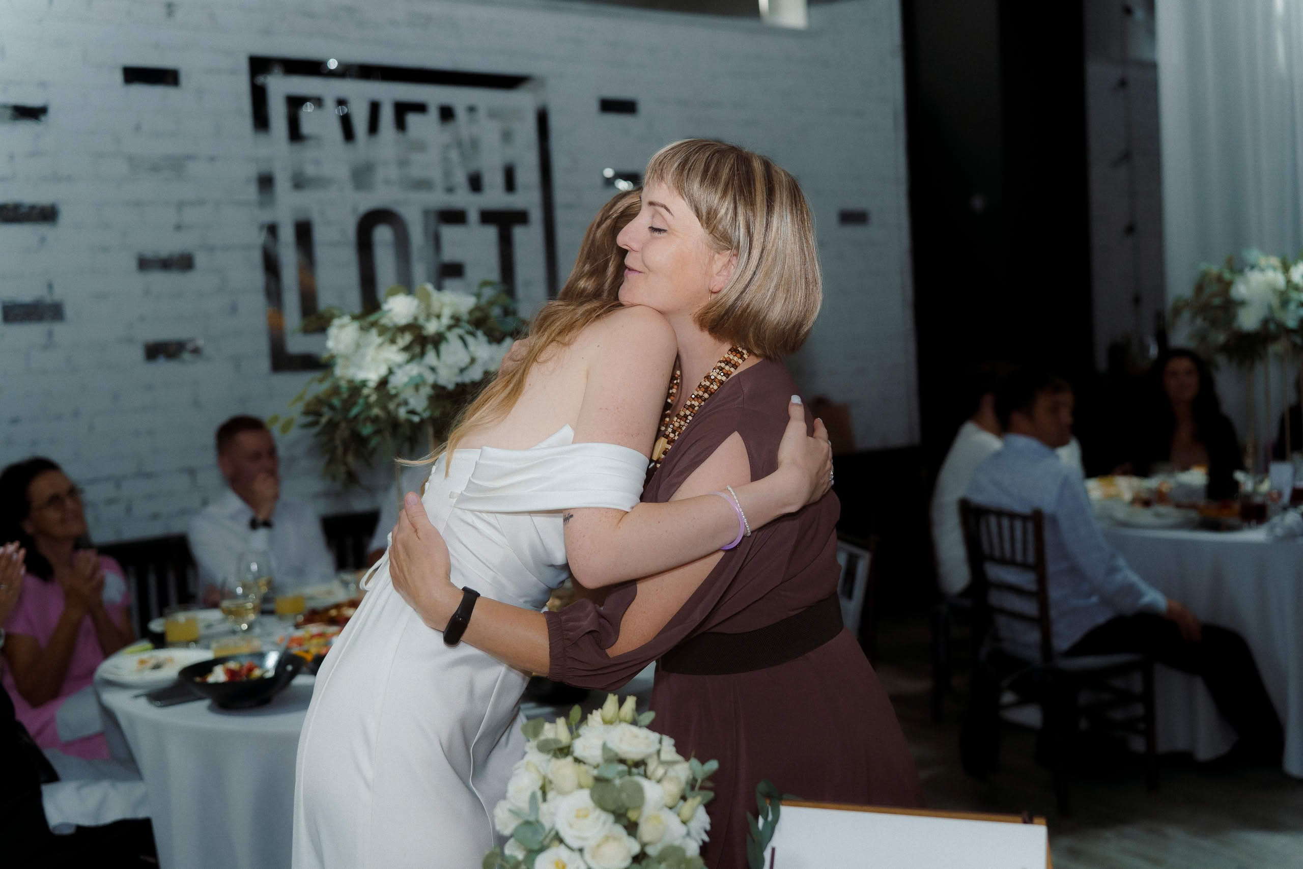 Объятия невесты Анны с гостьей на свадебном банкете