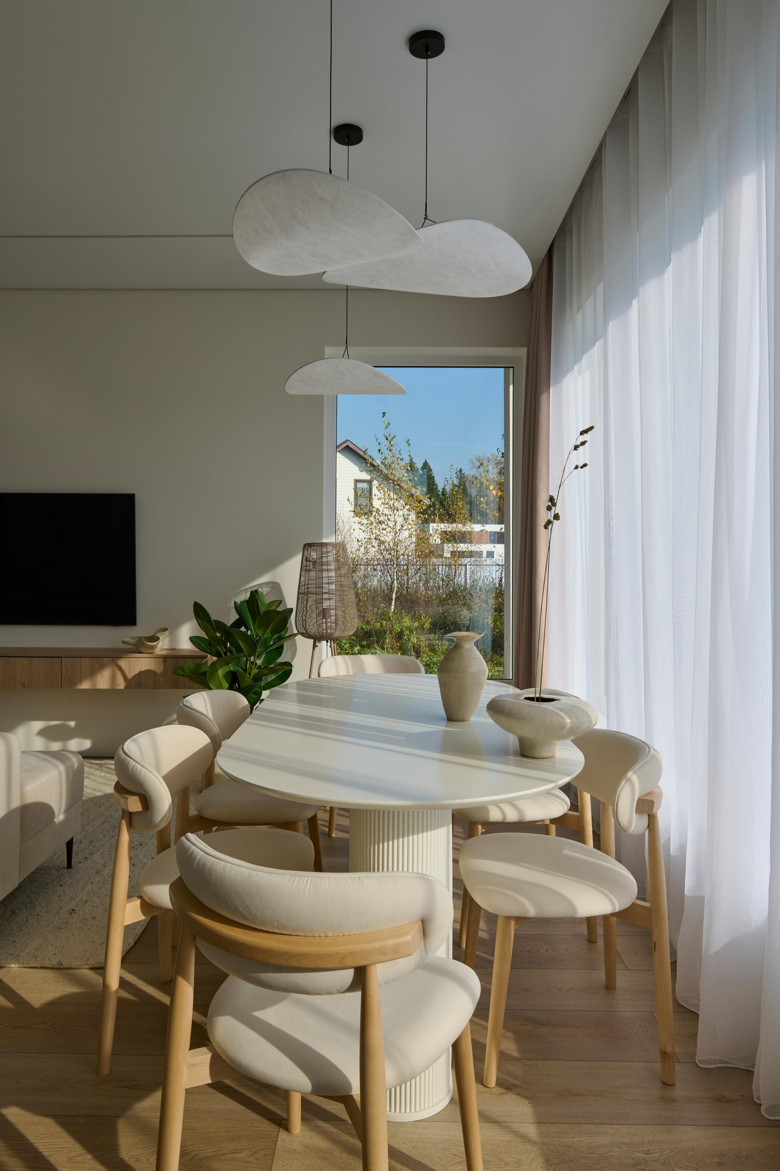 Обеденный стол и стулья, подвесные светильники и кухня на фоне