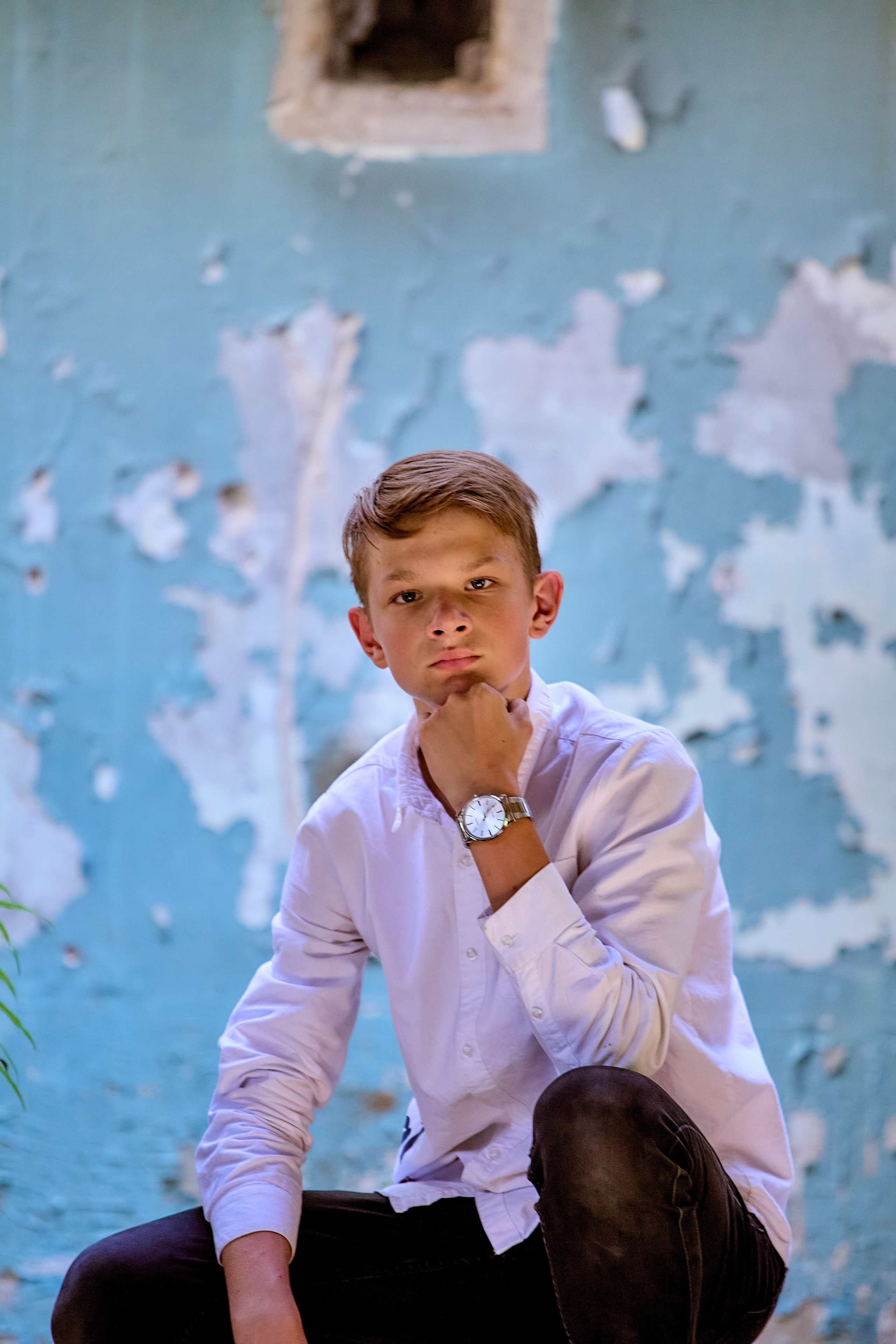 Парнишка на фоне крашеной облезлой стены в заброшенном здании