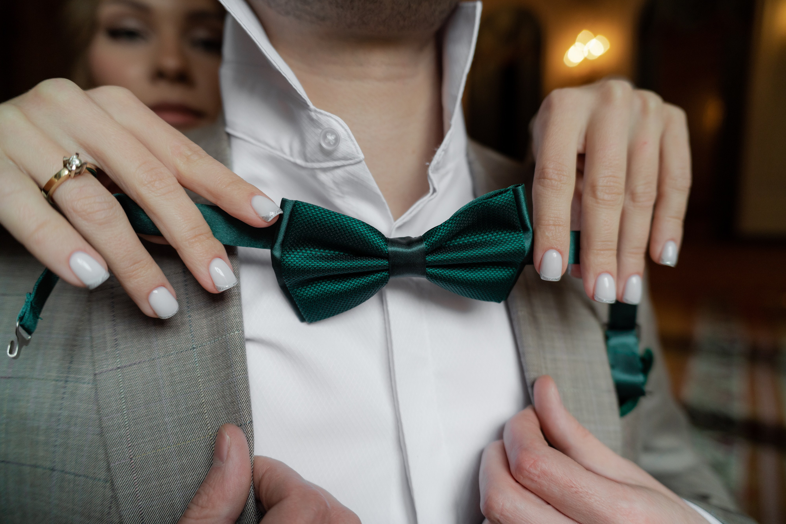 Невеста одевает зеленую бабочку жениху