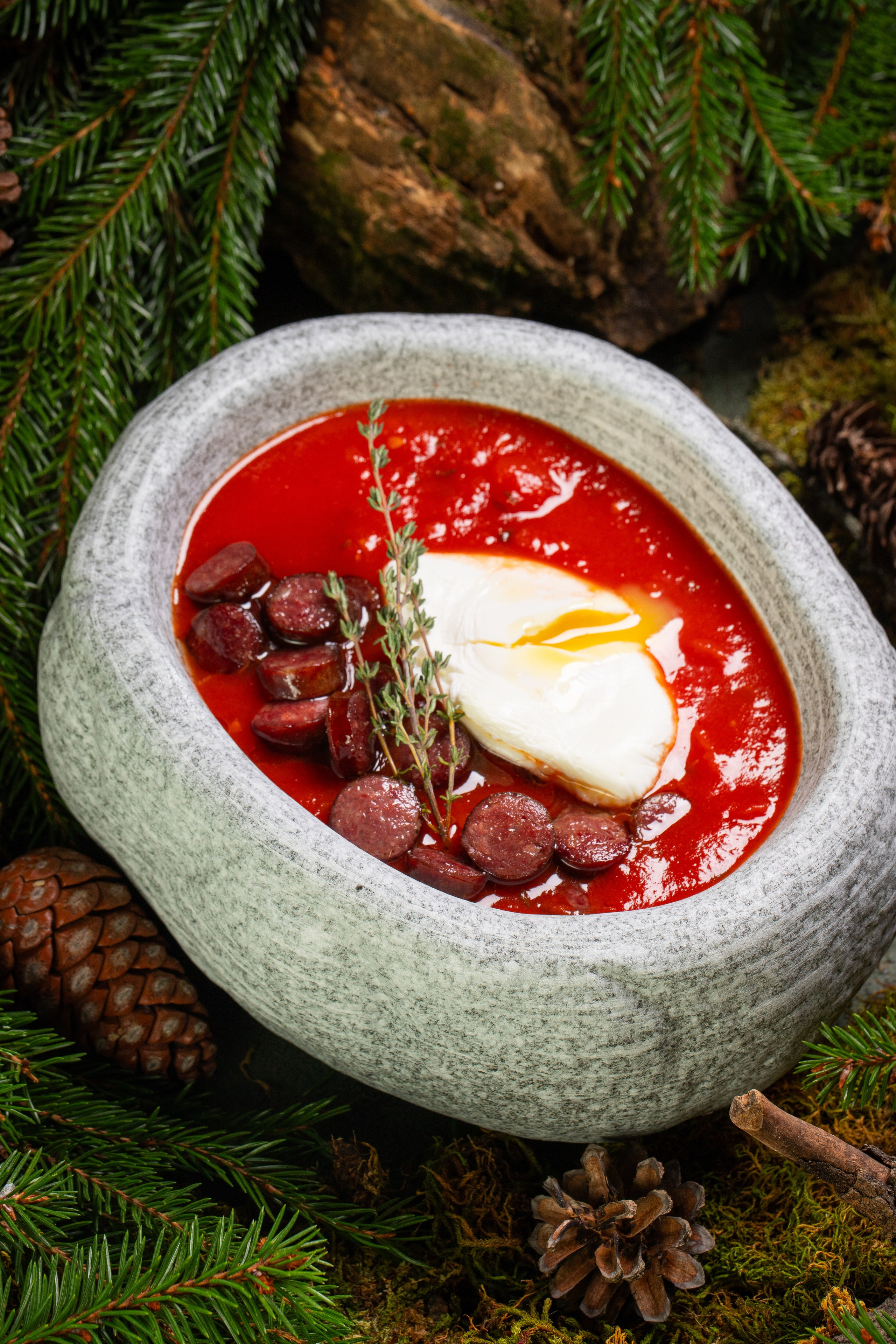 Суп с охотничьими колбасками с яйцом пашот в тарелке из камня. Стилизация для меню.