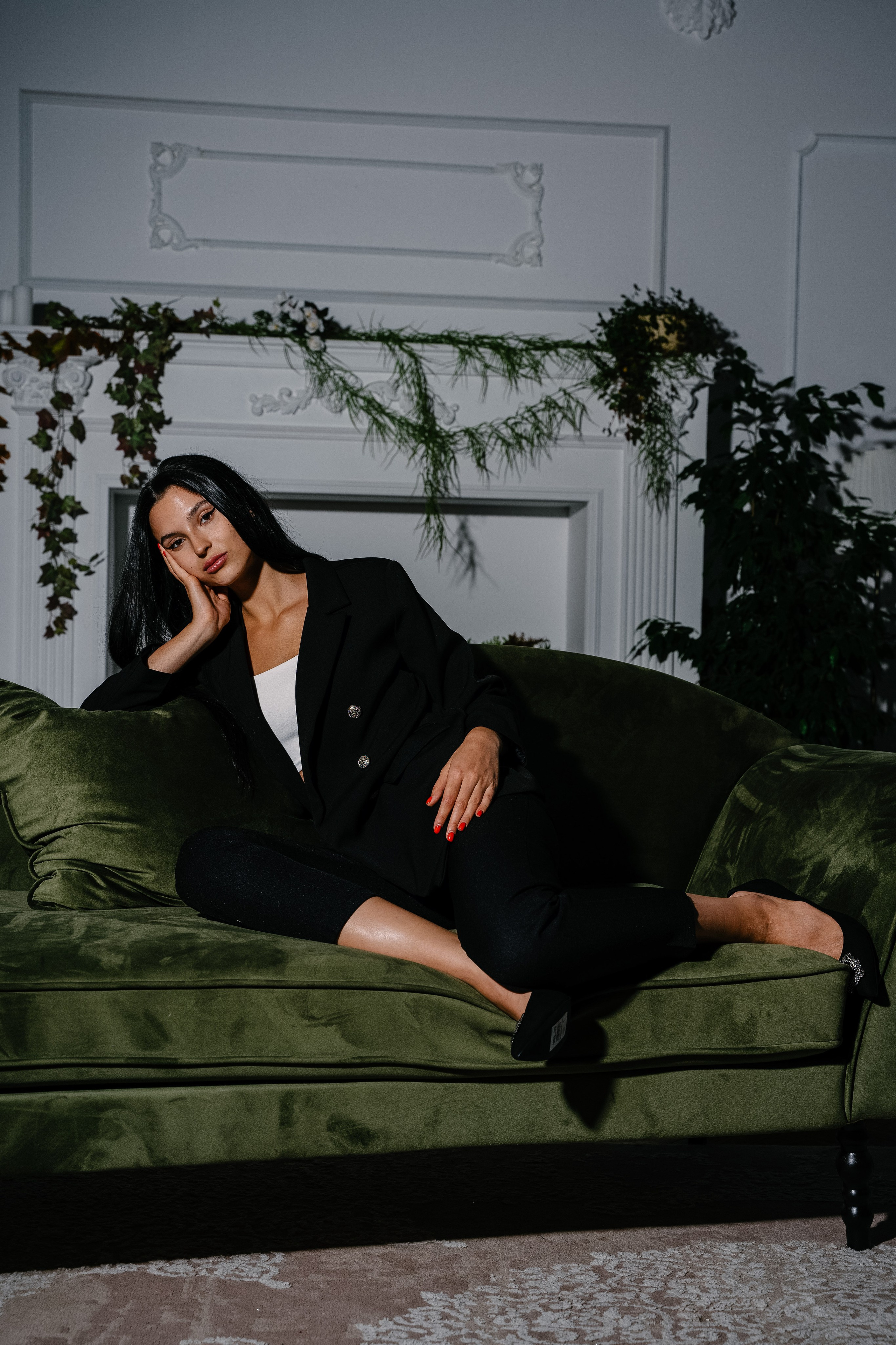 девушка в черном костюме сидит на зеленом диване красиво