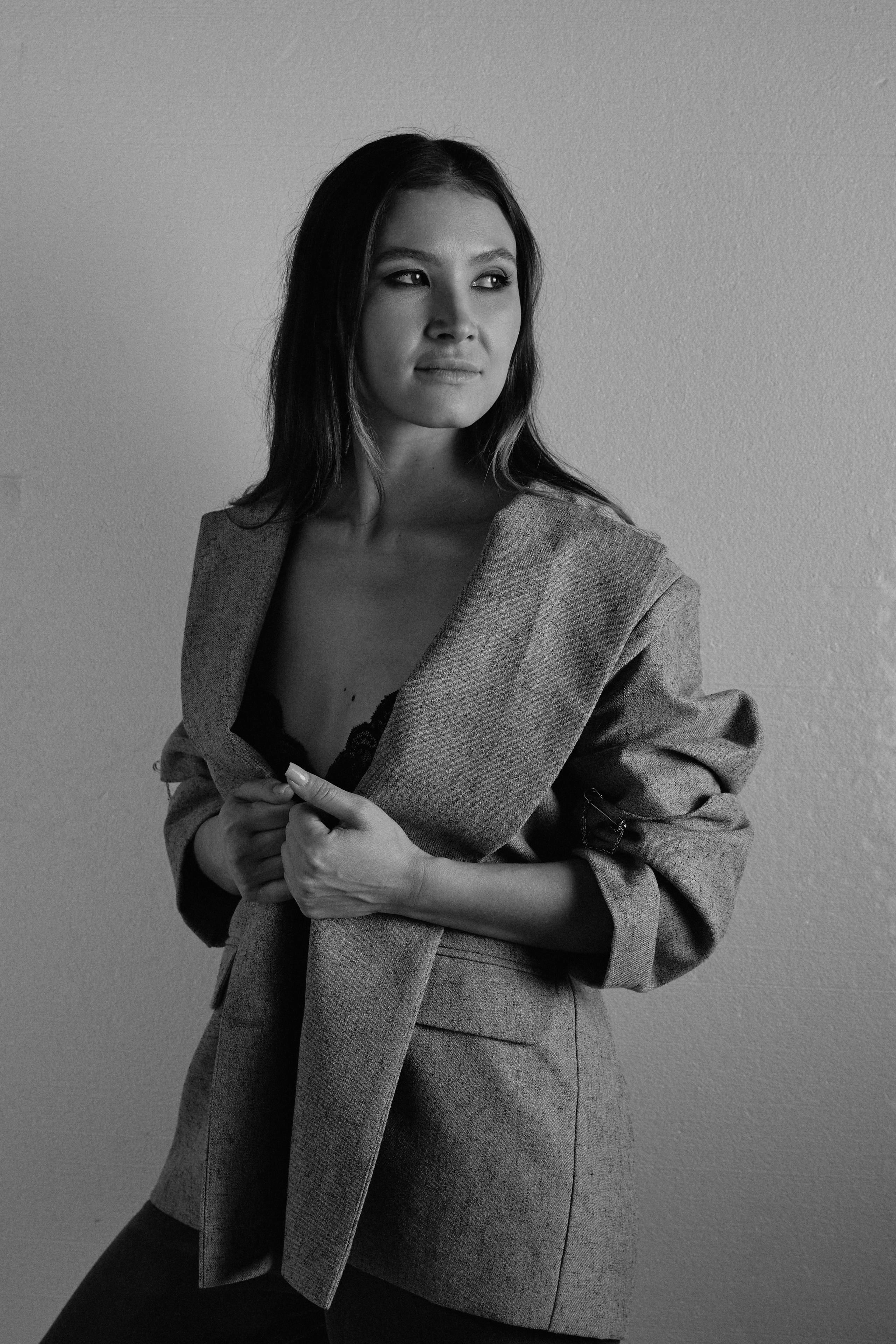 Черно-белая фотография девушка в сером пиджаке на белом фоне