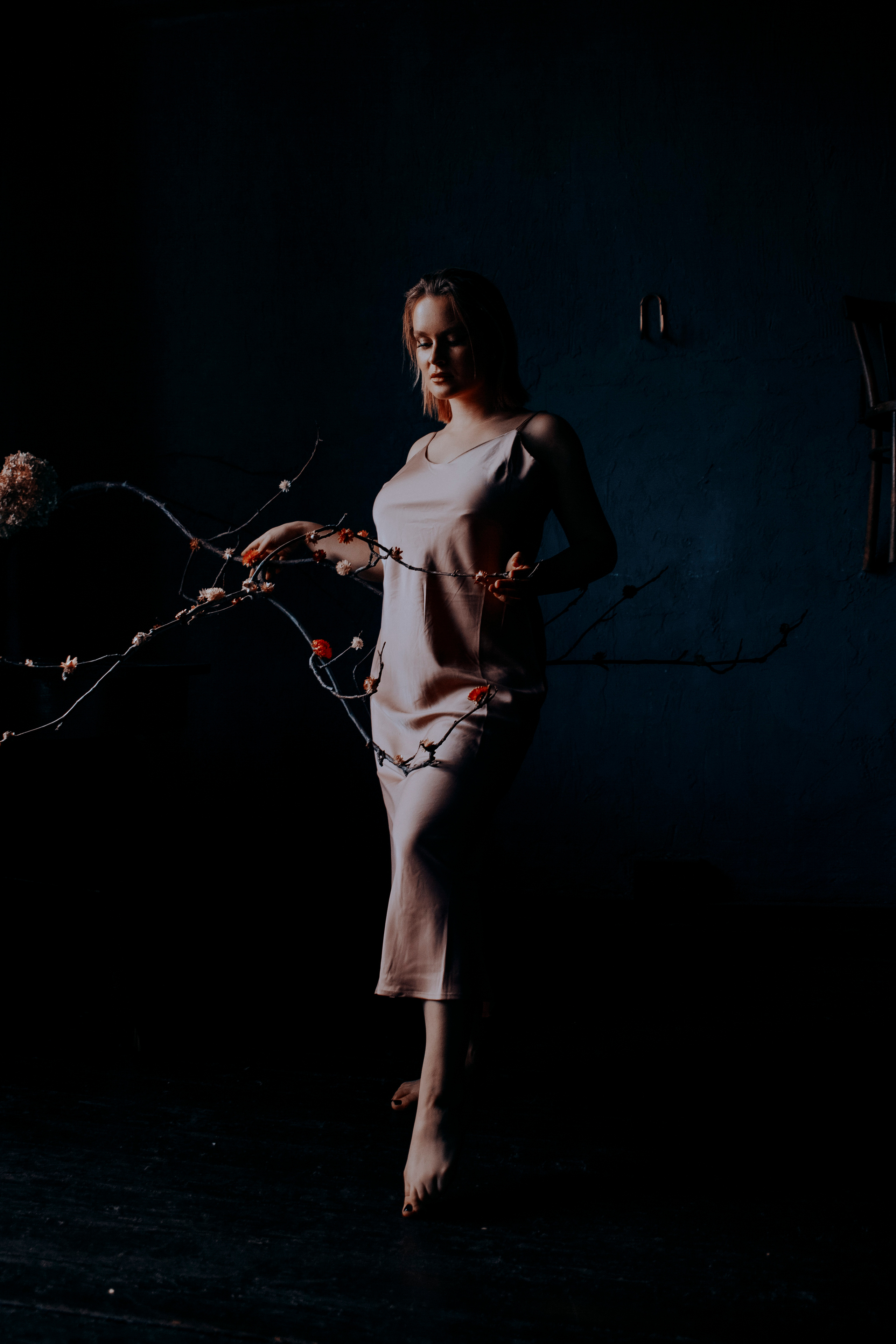 Девушка в темной комнате с цветами.