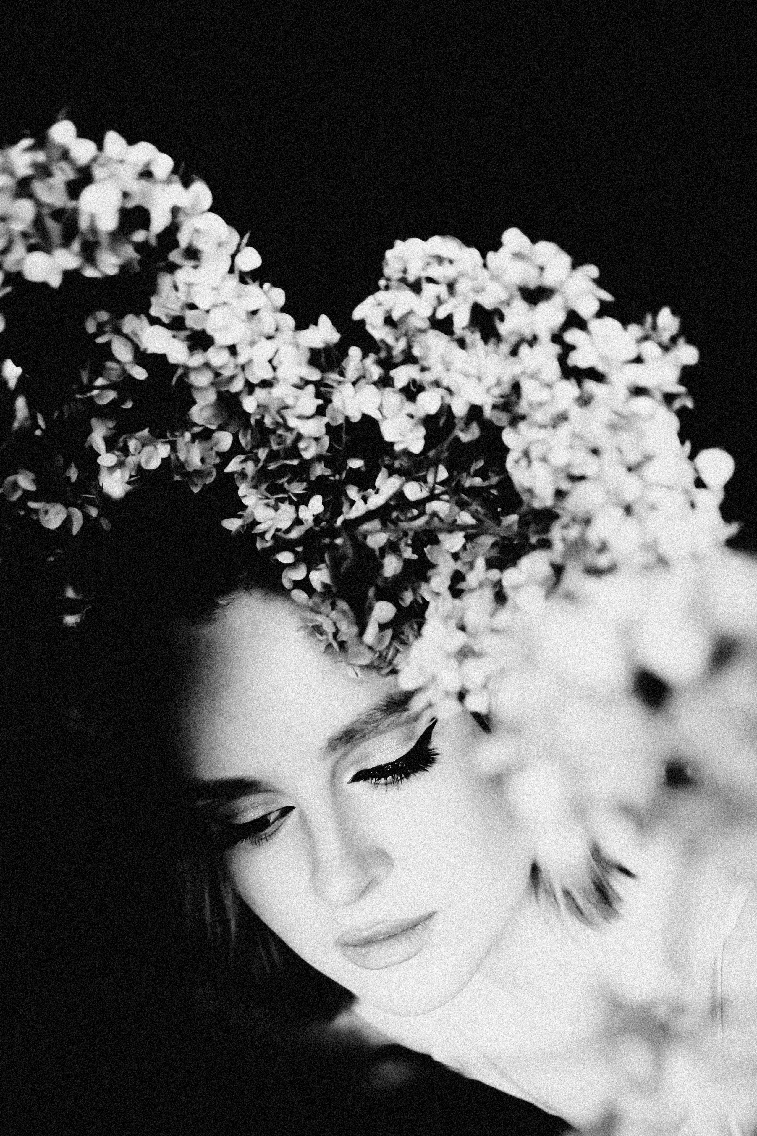 Черно-белый портрет девушки с цветами и черными стрелками.