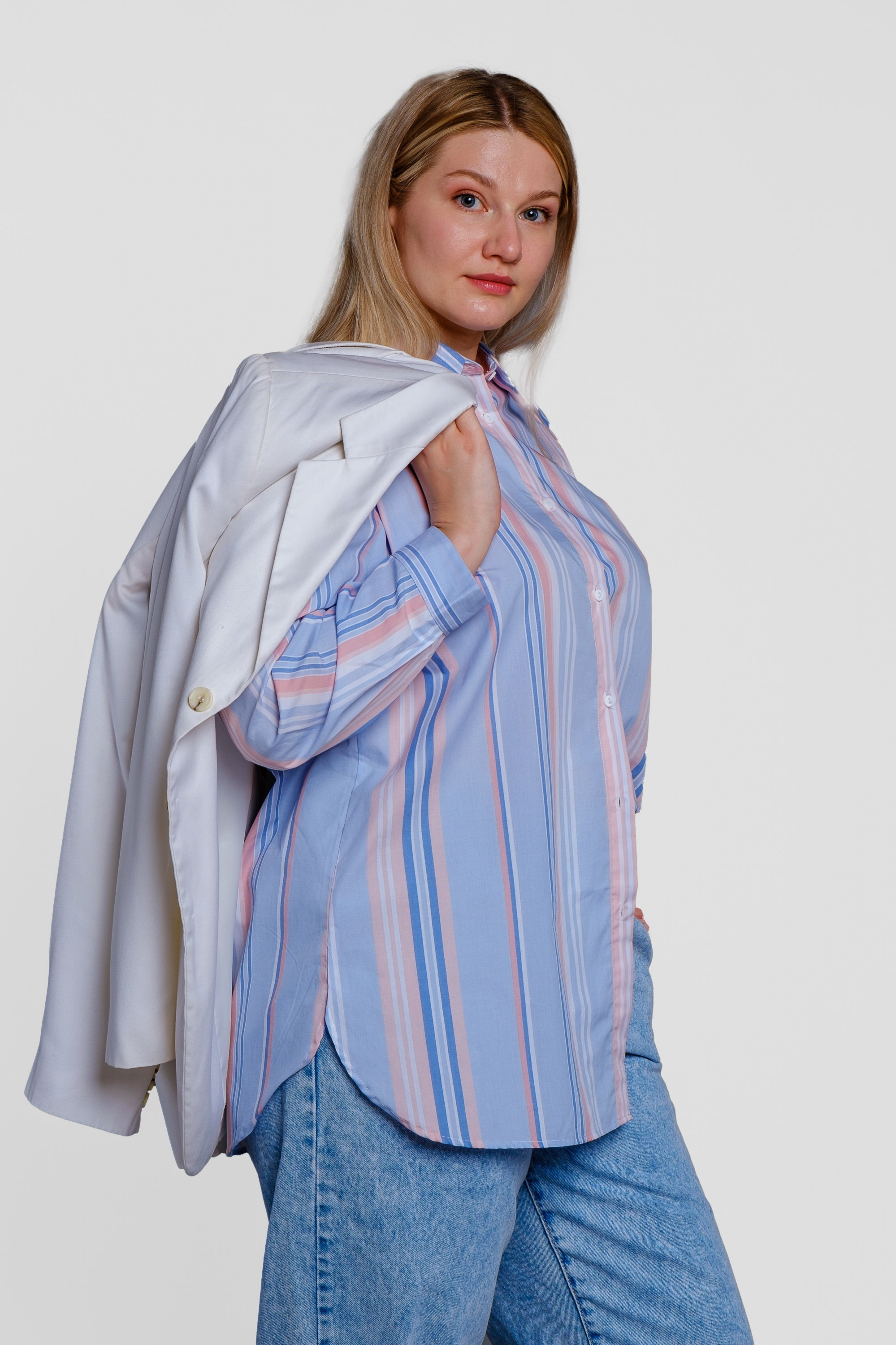 Девушка оверсайз в голубых брюках и белым пиджаком через плечо. Вид спереди. Фото для маркетплейсов