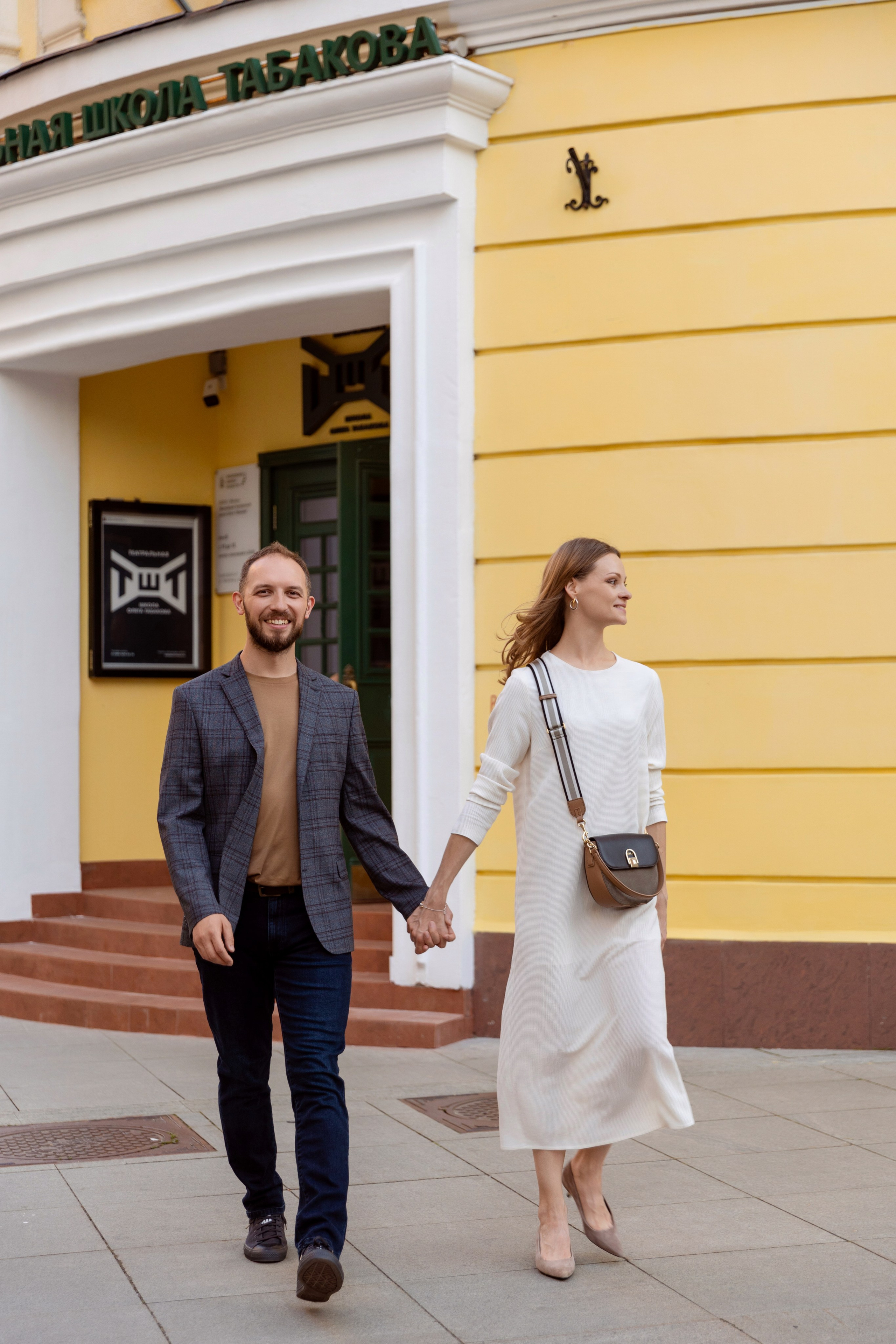 Жених и невеста идут по улице взявшись за руки.