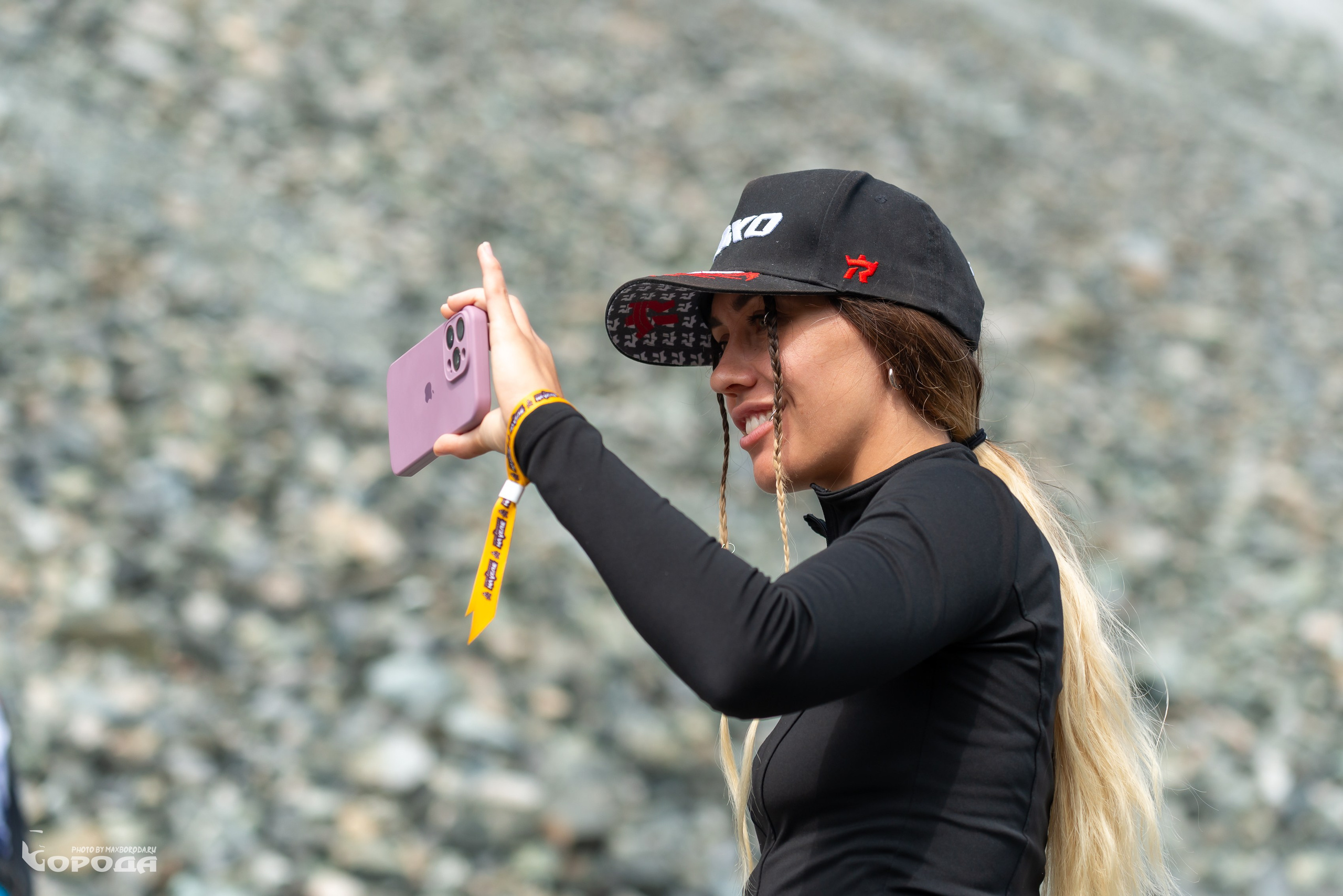 Красивая девушка с длинными косами фотографирует на телефон