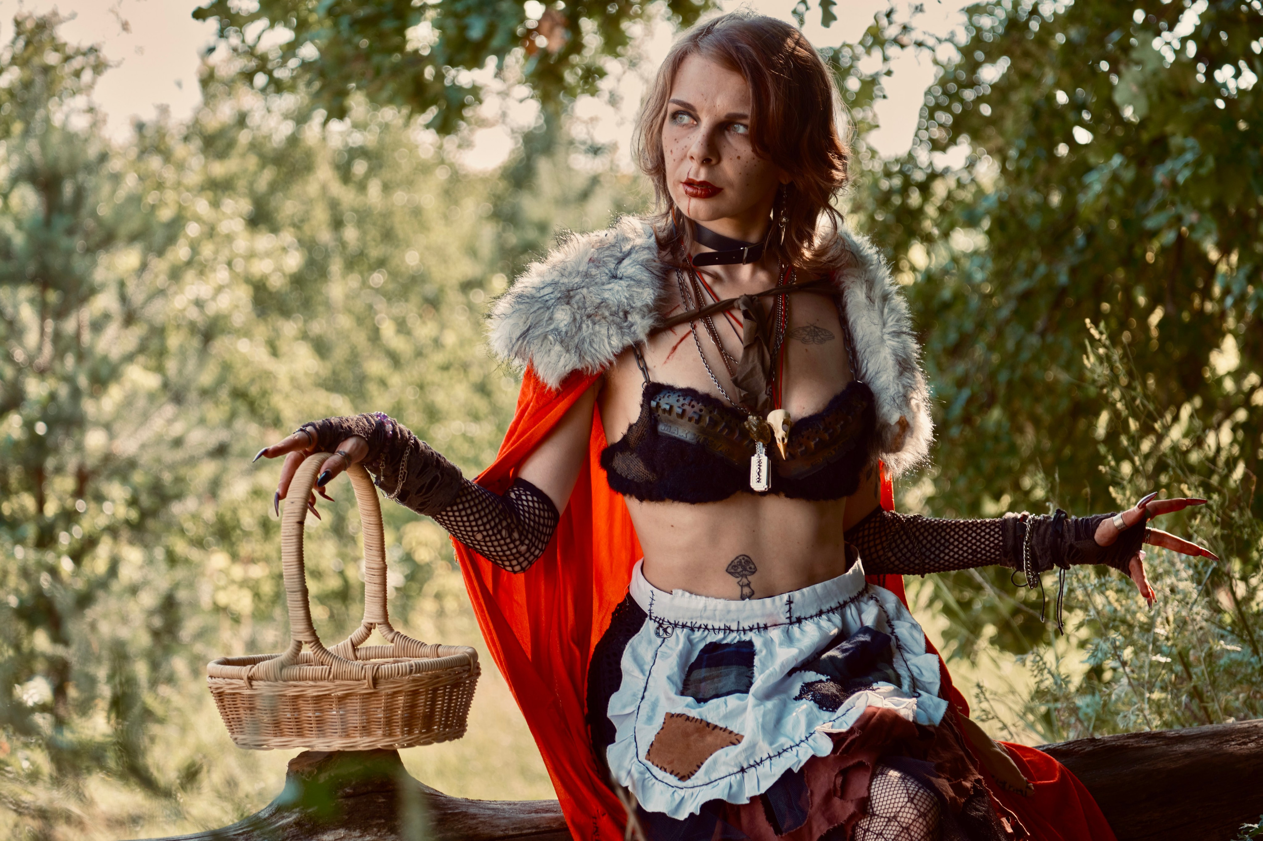 Девушка в красном плаще с корзиночкой и длинными ногтями гуляет в лесу