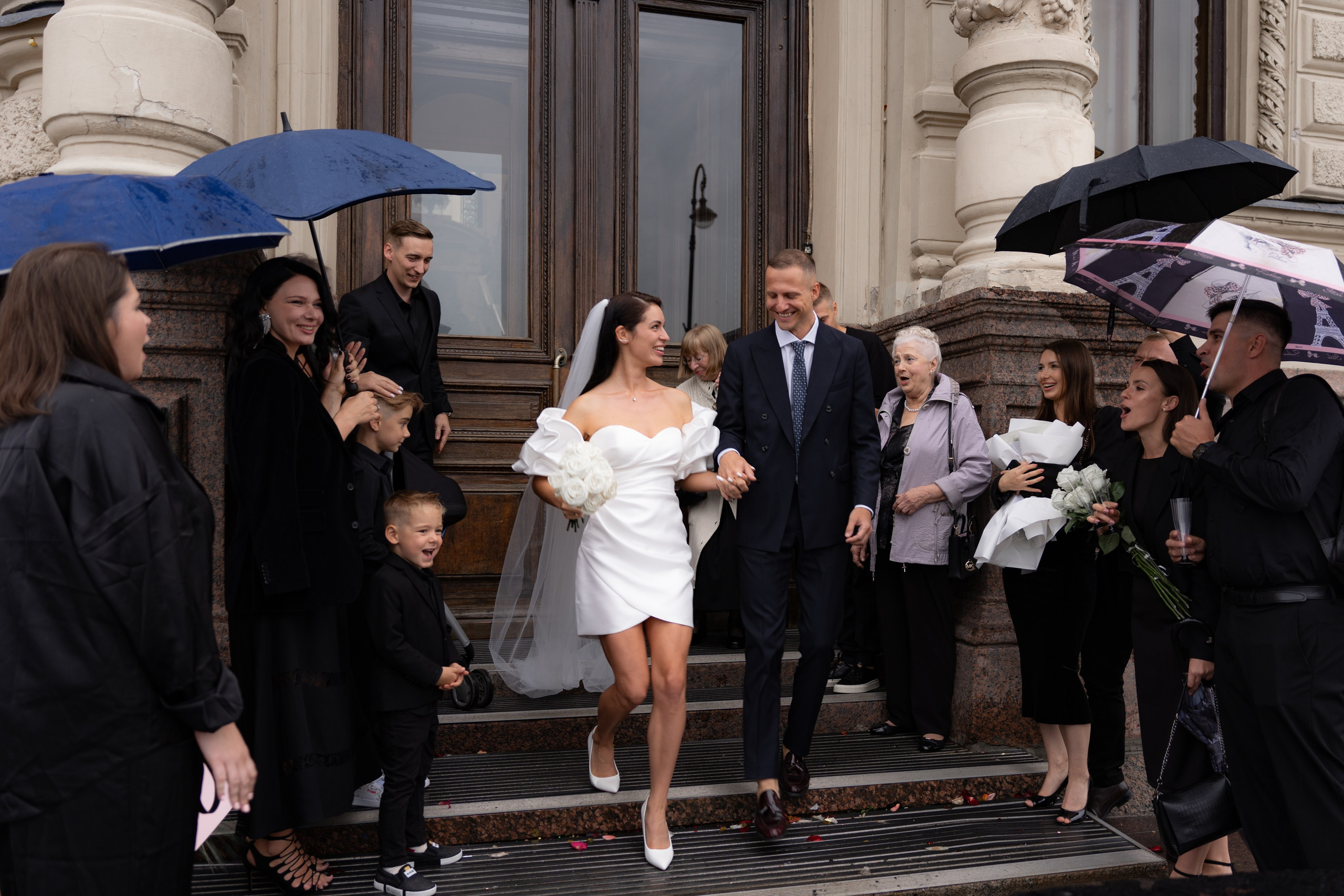жениха и невеста под зонтиками на выходе из дворца 1 на английской набережной выходят после регистрации брака