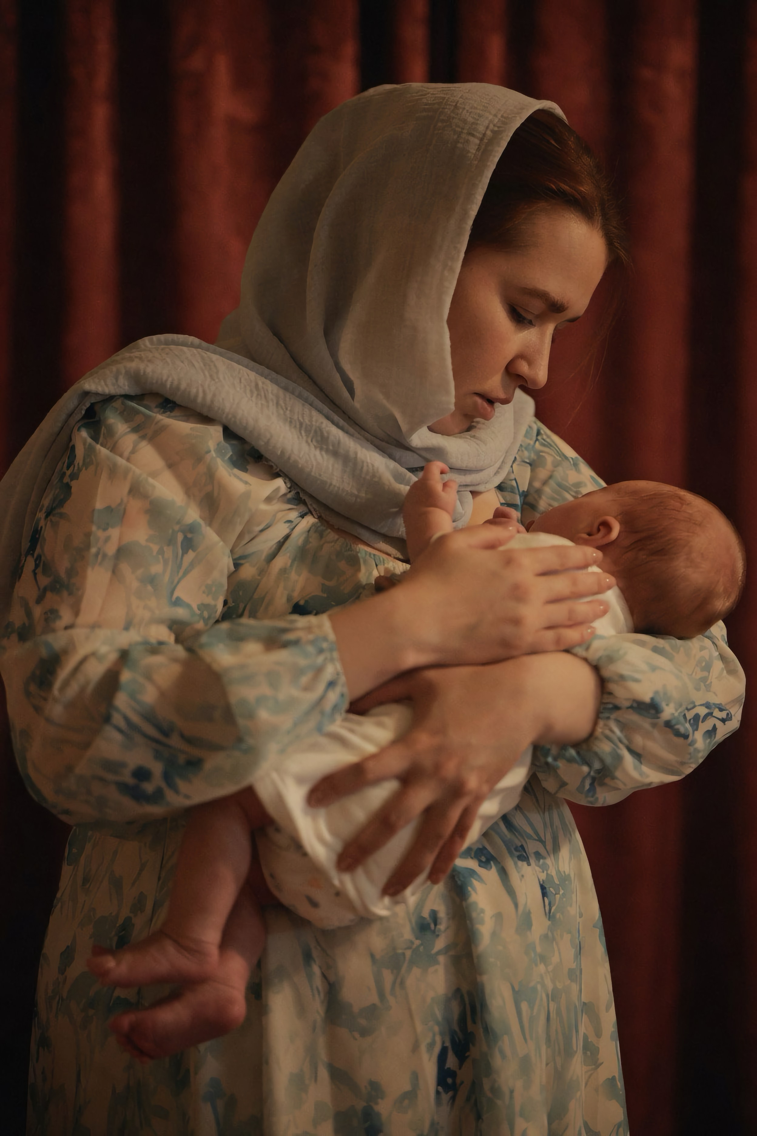 Мать в голубом плате держит новорождённого после крещения, бордовый занавес, тёплый плёночный свет — Екатеринбург, Илья Антропов