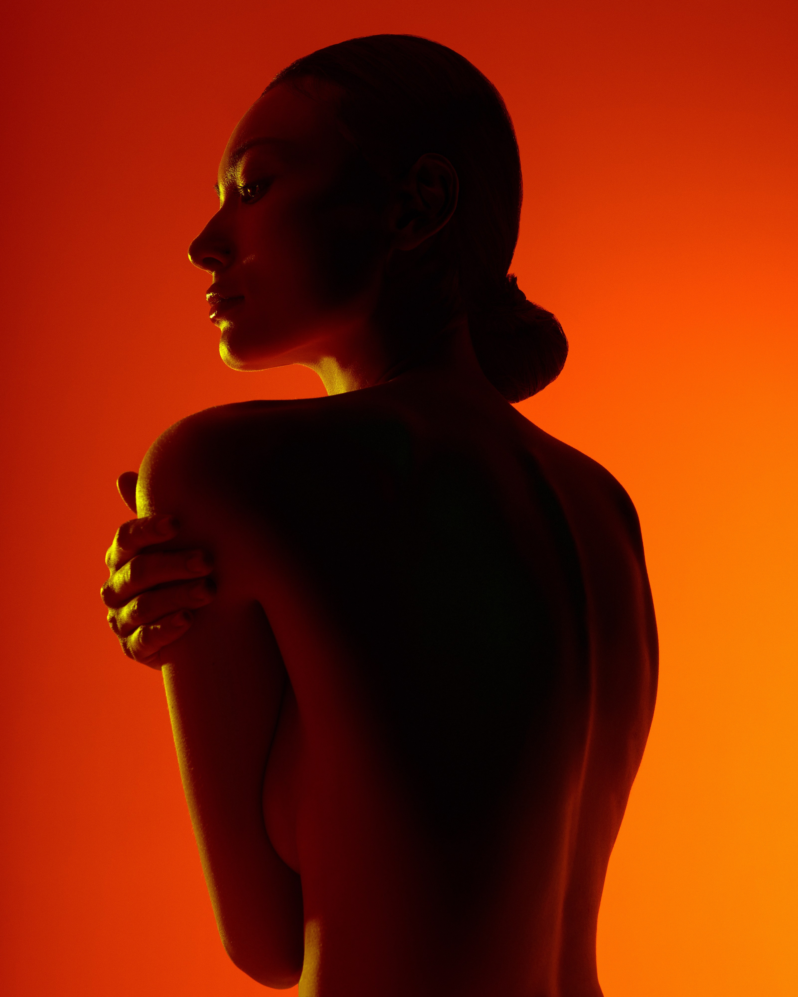 Фэшн фотография с обнажённой девушкой азиатской внешности подсвеченная контурным тёплым светом