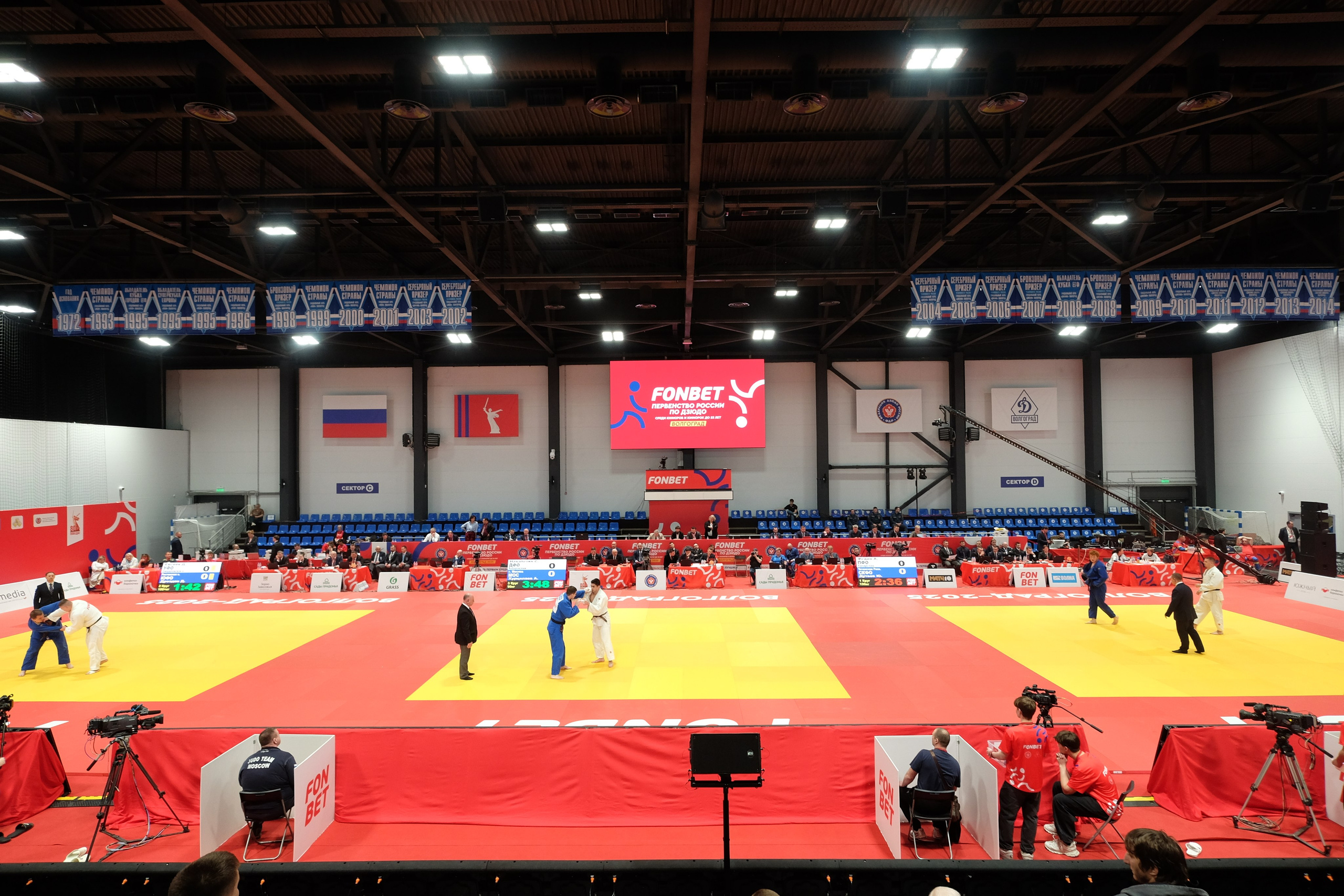 Гимнастка выполняет акробатический элемент «колесо» на помосте с матами в зале спортивной школы во время отчётного выступления