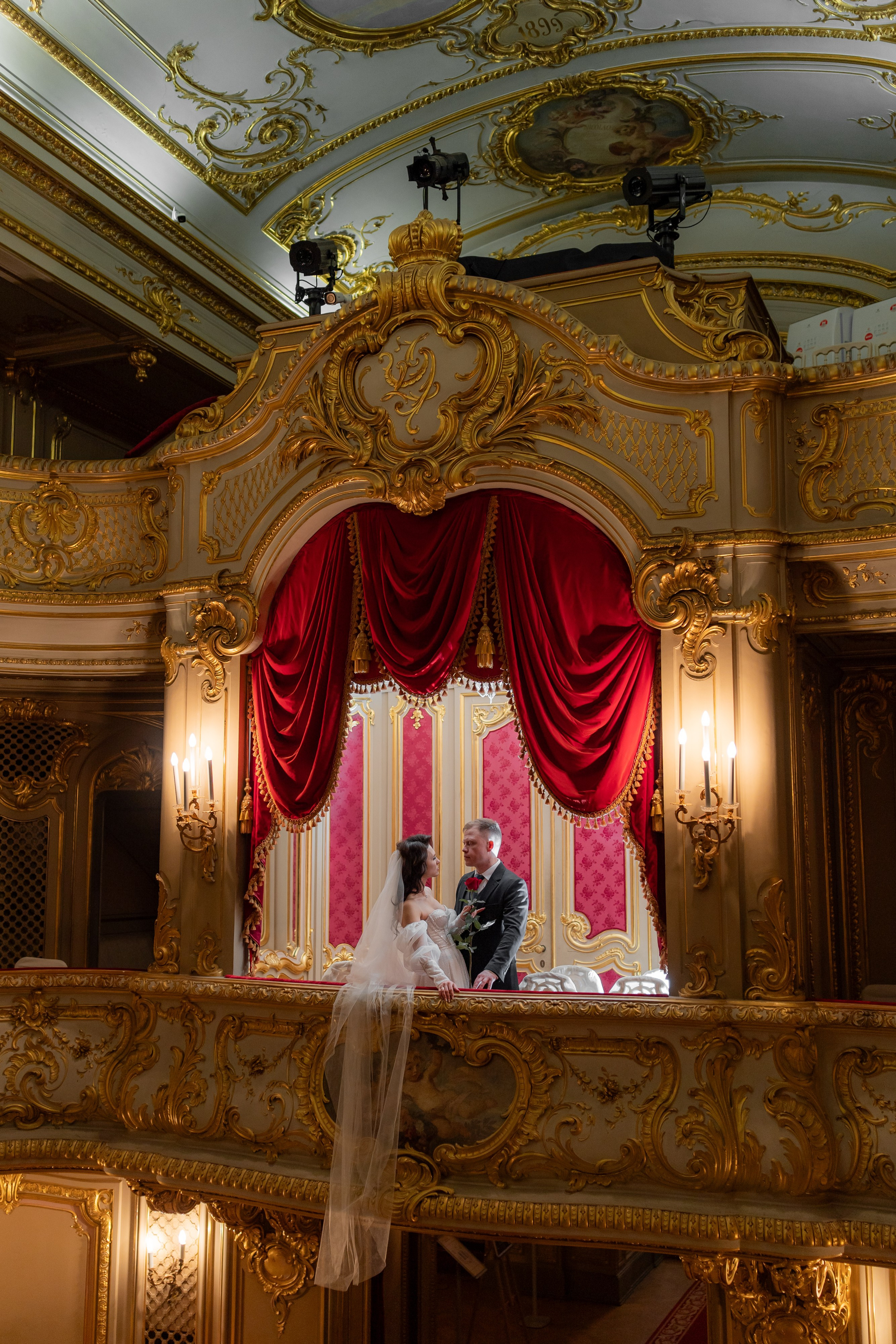 Жених красиво целует невесту с фатой переброшенной за ограждение в ложе театра Юсуповского дворца