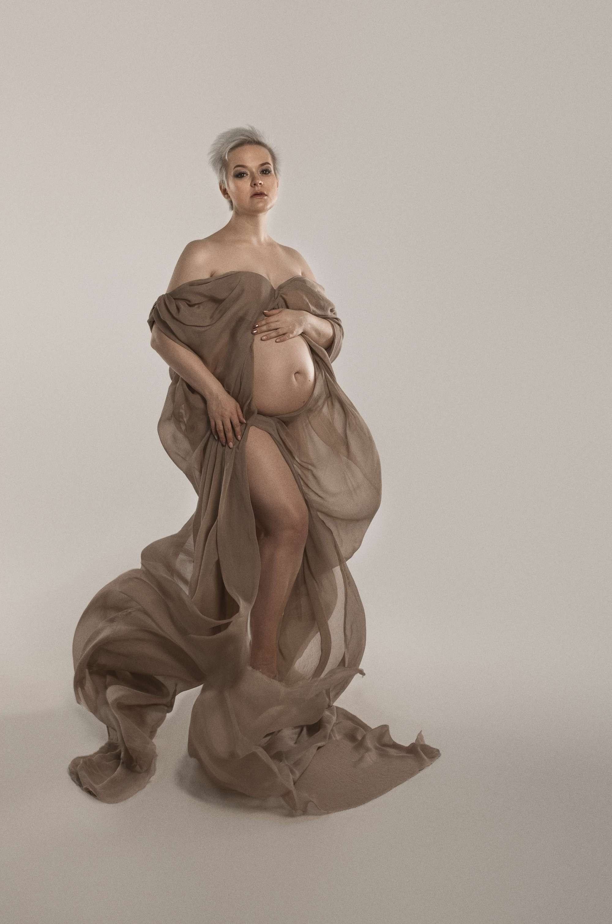 фотосессия беременной в фотостудии на светлом фоне в красивом разлетающемся платье, фотография беременности, фотосессия беременных, портрет беременной