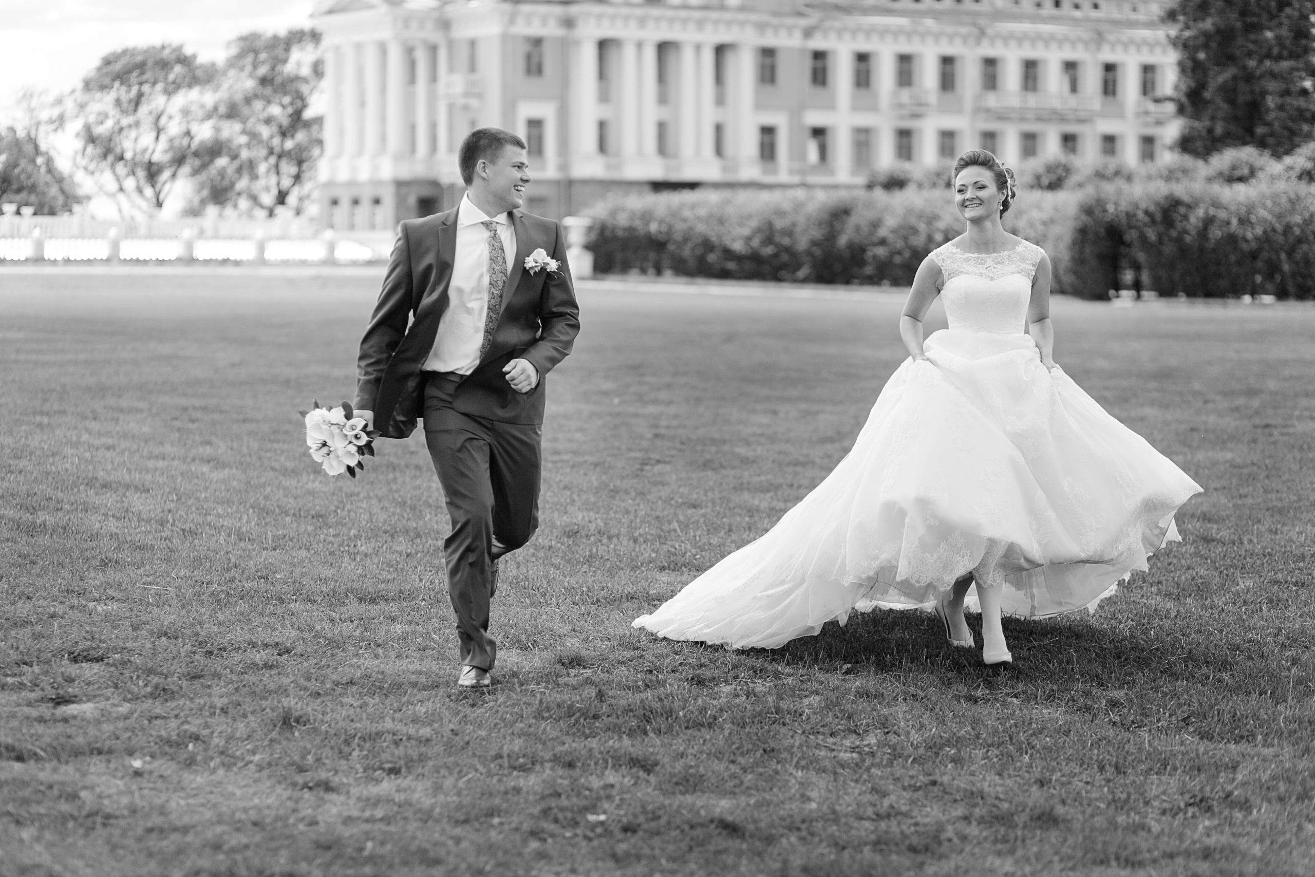 Жених и невеста вместе бегут по зелёному газону