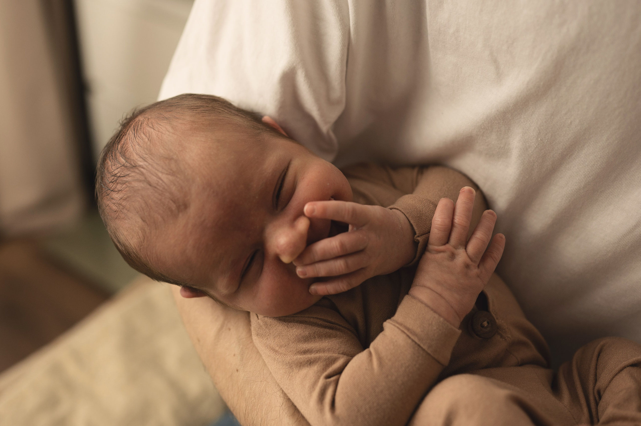 Новорожденный малыш улыбается у папы на руках