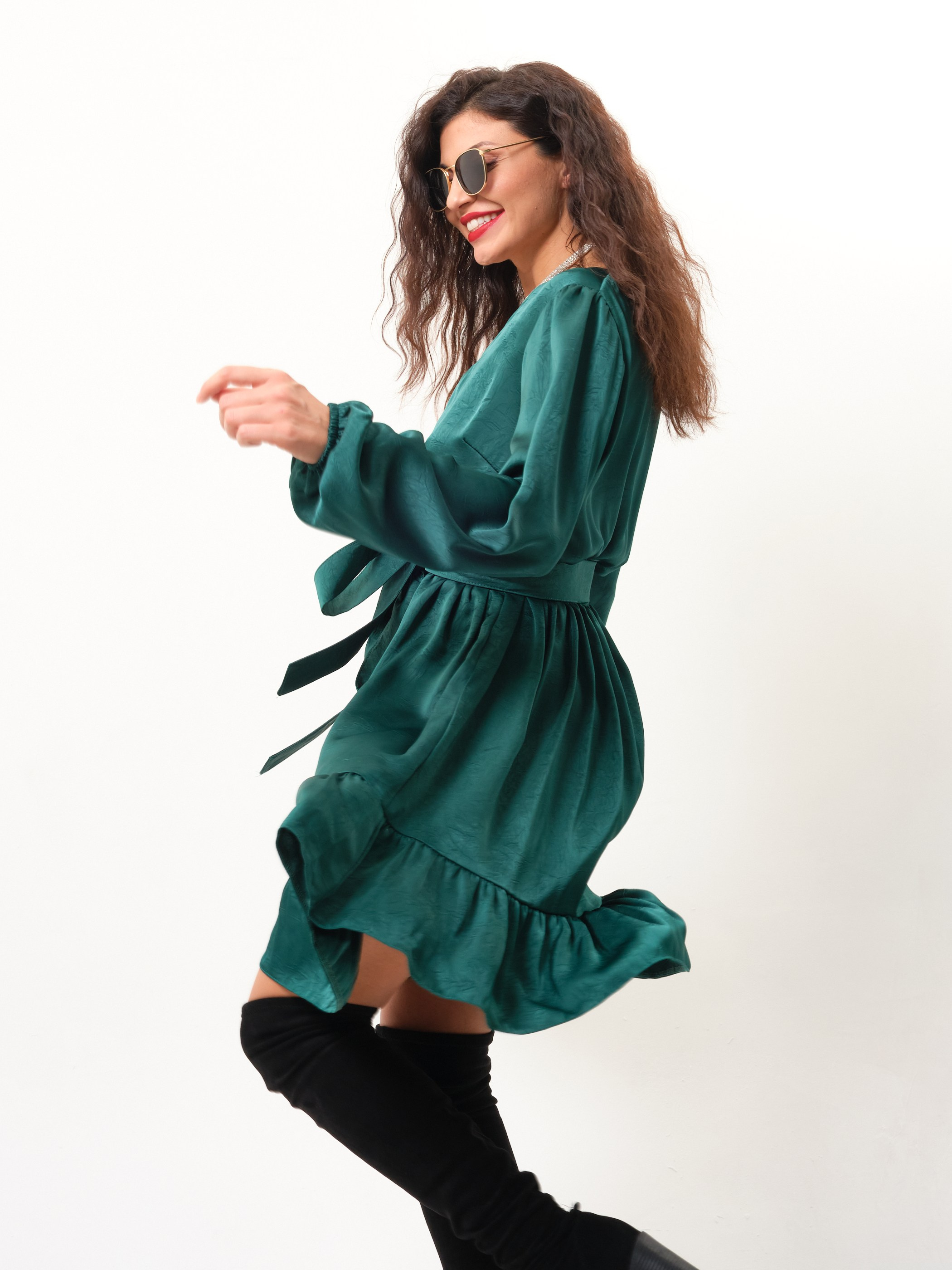 Кудрявая девушка в высоких сапогах и легком зеленом платье