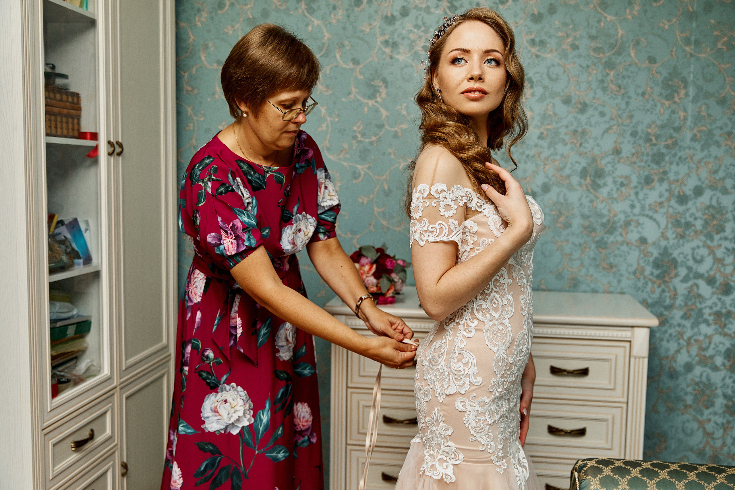 мама проявляет заботу застегивая свадебное платье своей дочери 