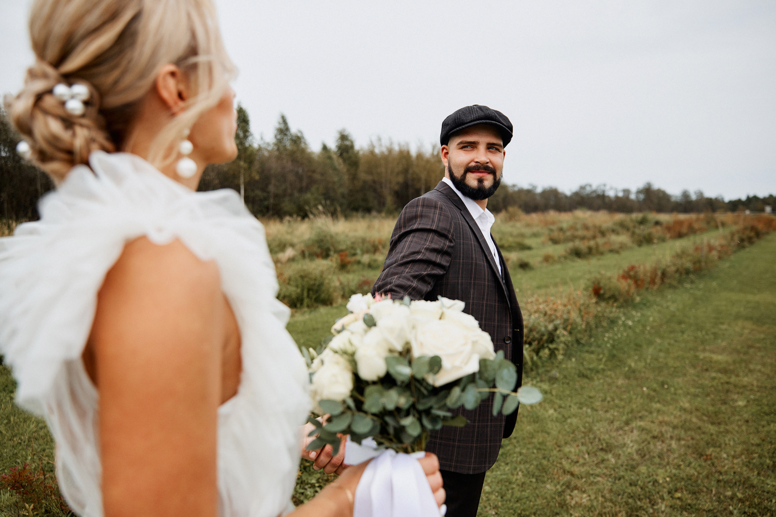 Красивый жених ведет за собой невесты на фотосессию 