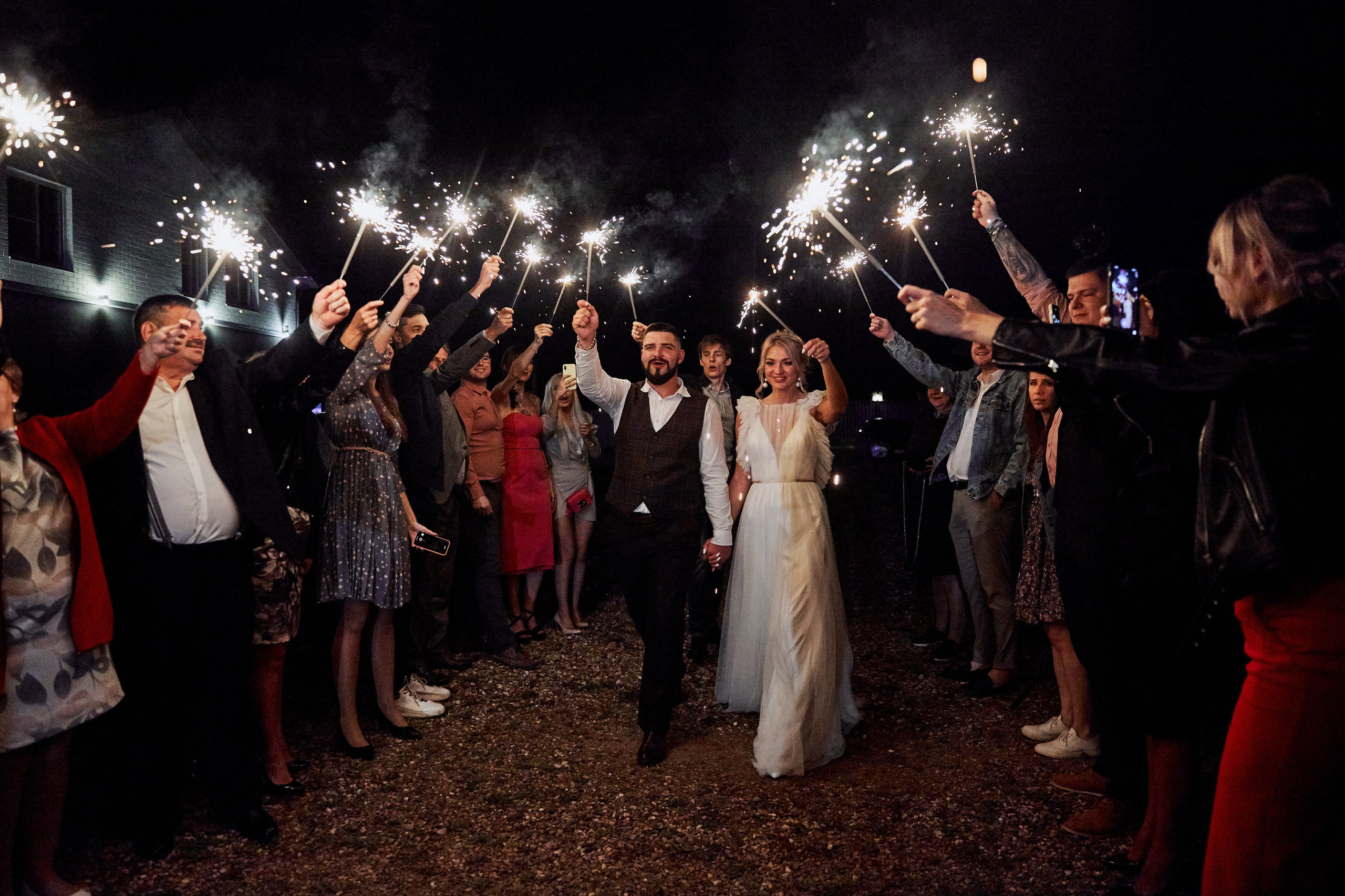 молодая пара идет по коридору из бенгальских огней