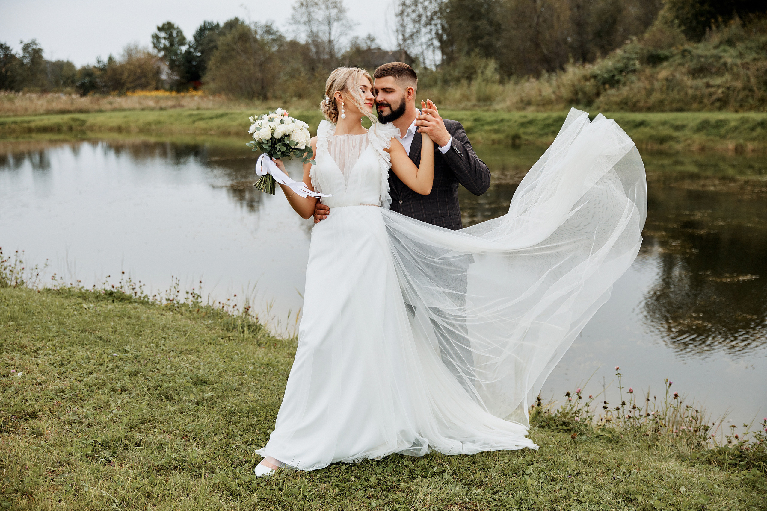 Развивающиеся платье невесты в объятьях жених