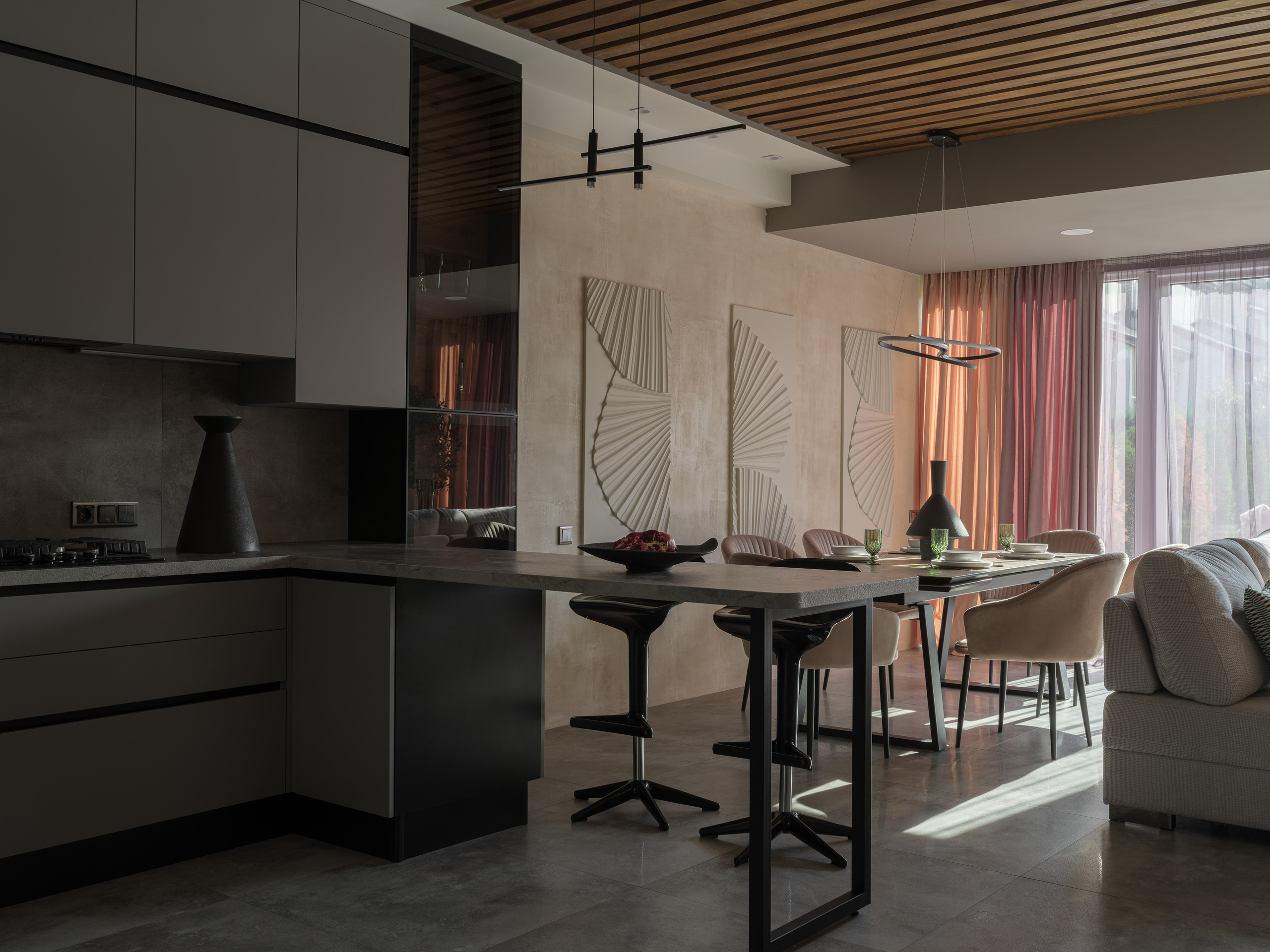 Интерьер кухни-гостиной в нейтральных тонах с мягким дневным светом и настенными 3D-панелями. Дизайн Алины Дёровой и стилистика Натальи Якушевой, снятые Сергеем Денисенко, подчёркивают гармонию текстур и архитектуры.