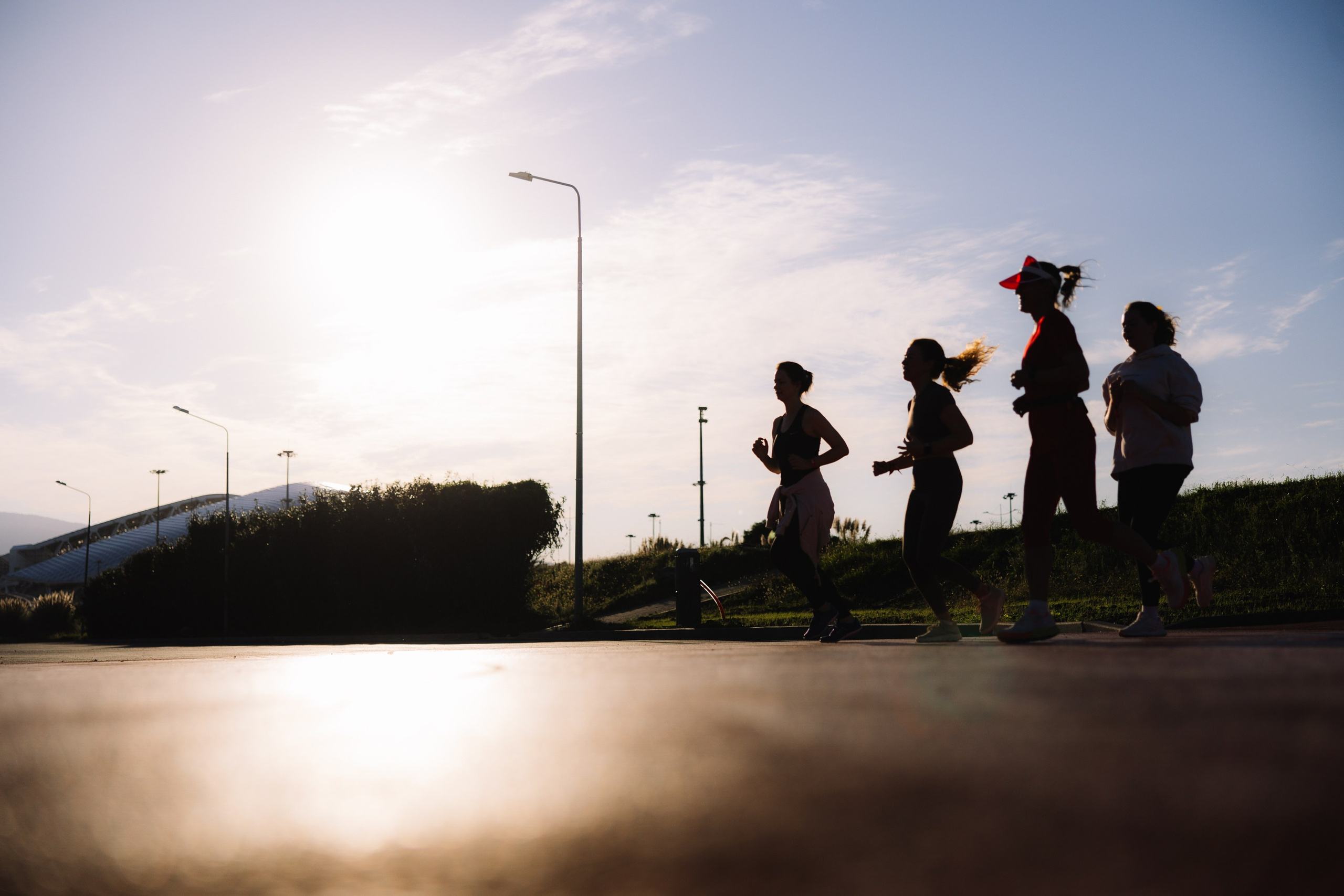 Старт: Силуэты спортсменов на стартовой линии в контровом свете солнца.