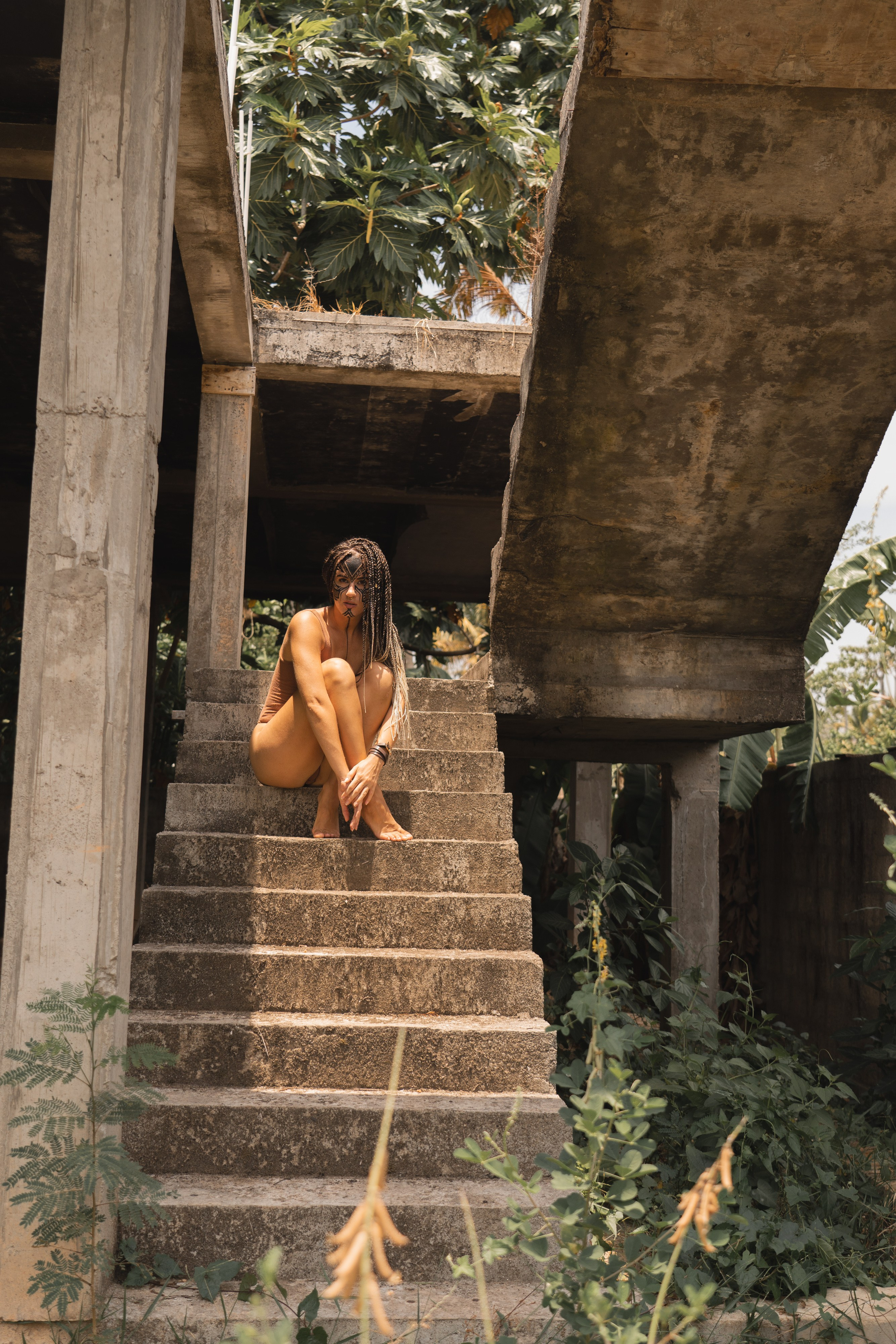 a girl with braids and patterned face paint standing in the wild jungle