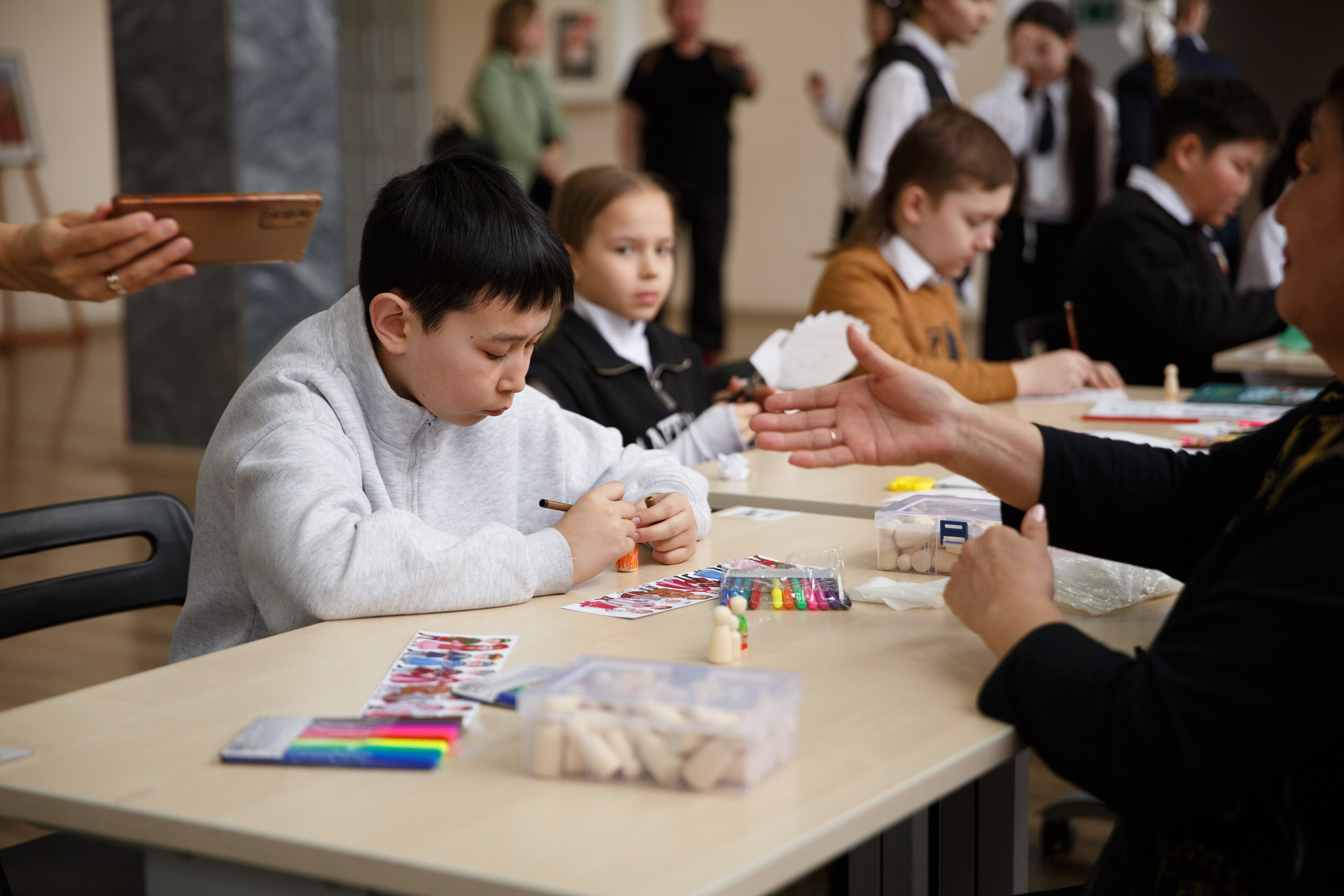 Два мальчика занимаются творчеством на столе.