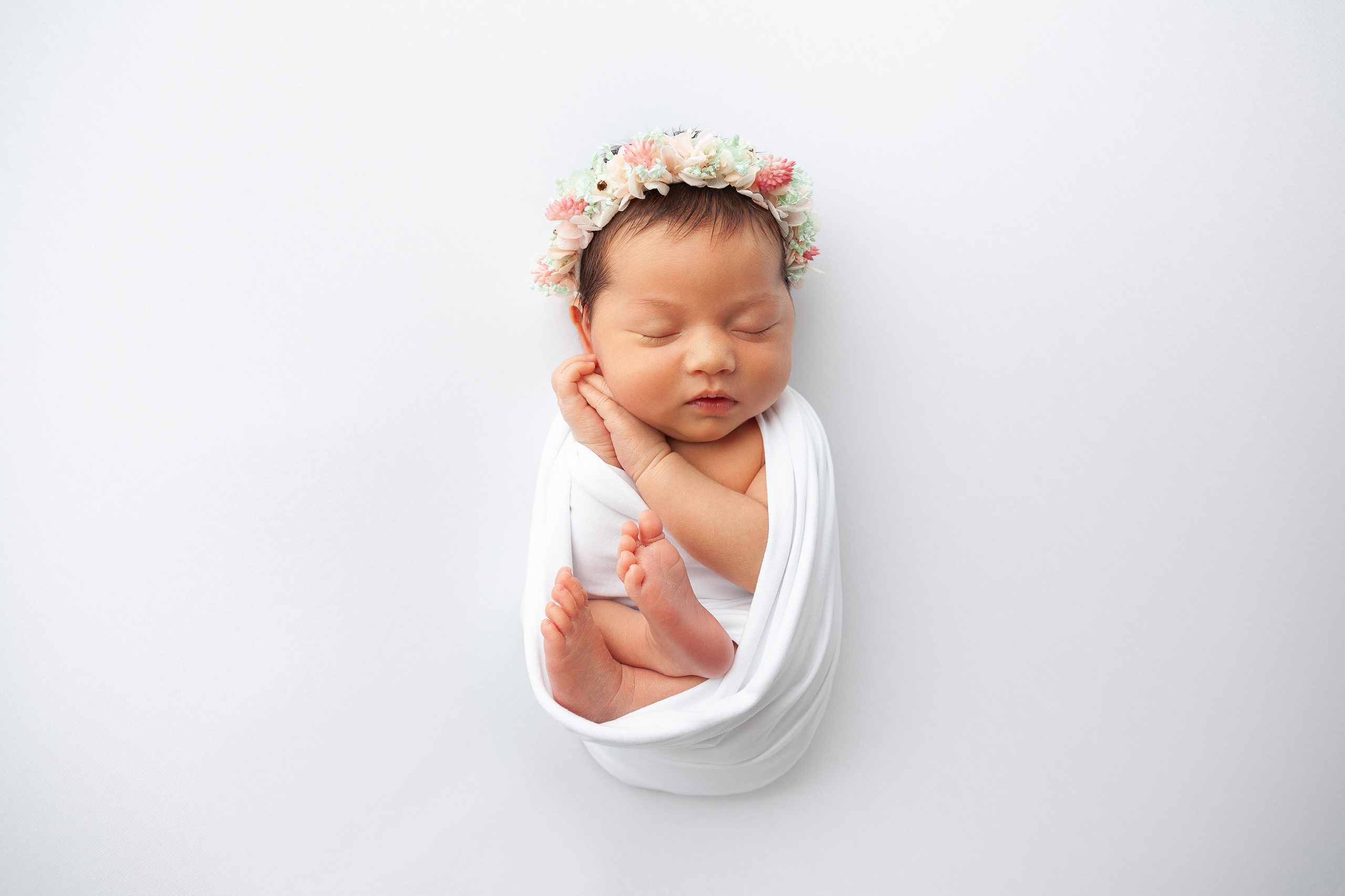 новорожденная девочка на белом фонес цветочным веночком