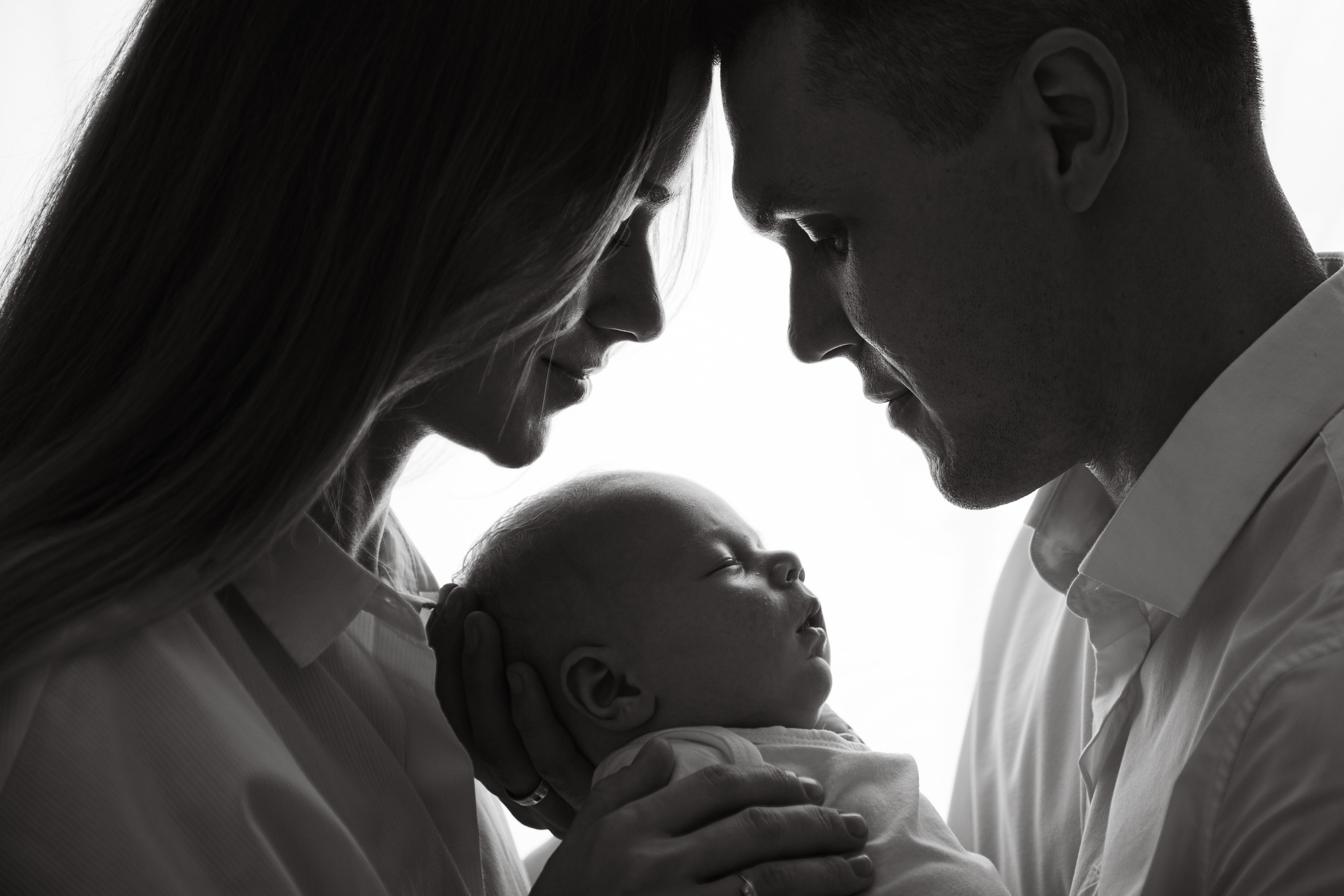 черно-белый семейный портрет с новорожденным в фотостудии на белом фоне 