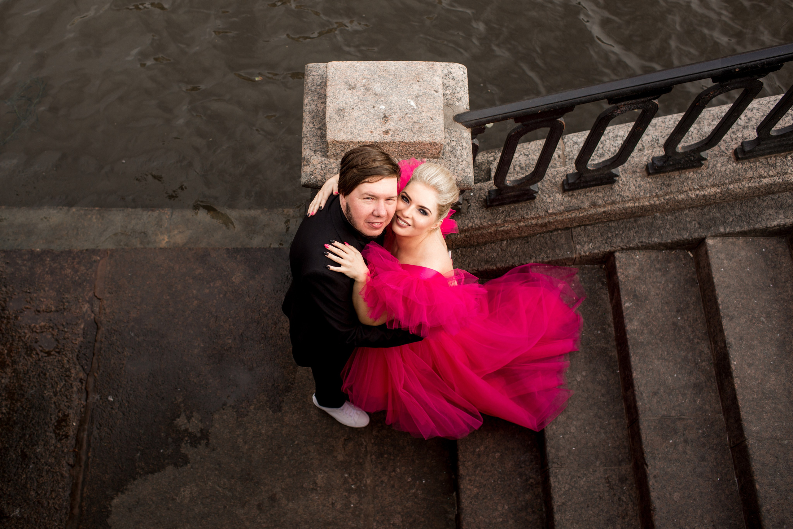 Элегантная невеста в свадебном платье обнимает жениха в центре Петербурга