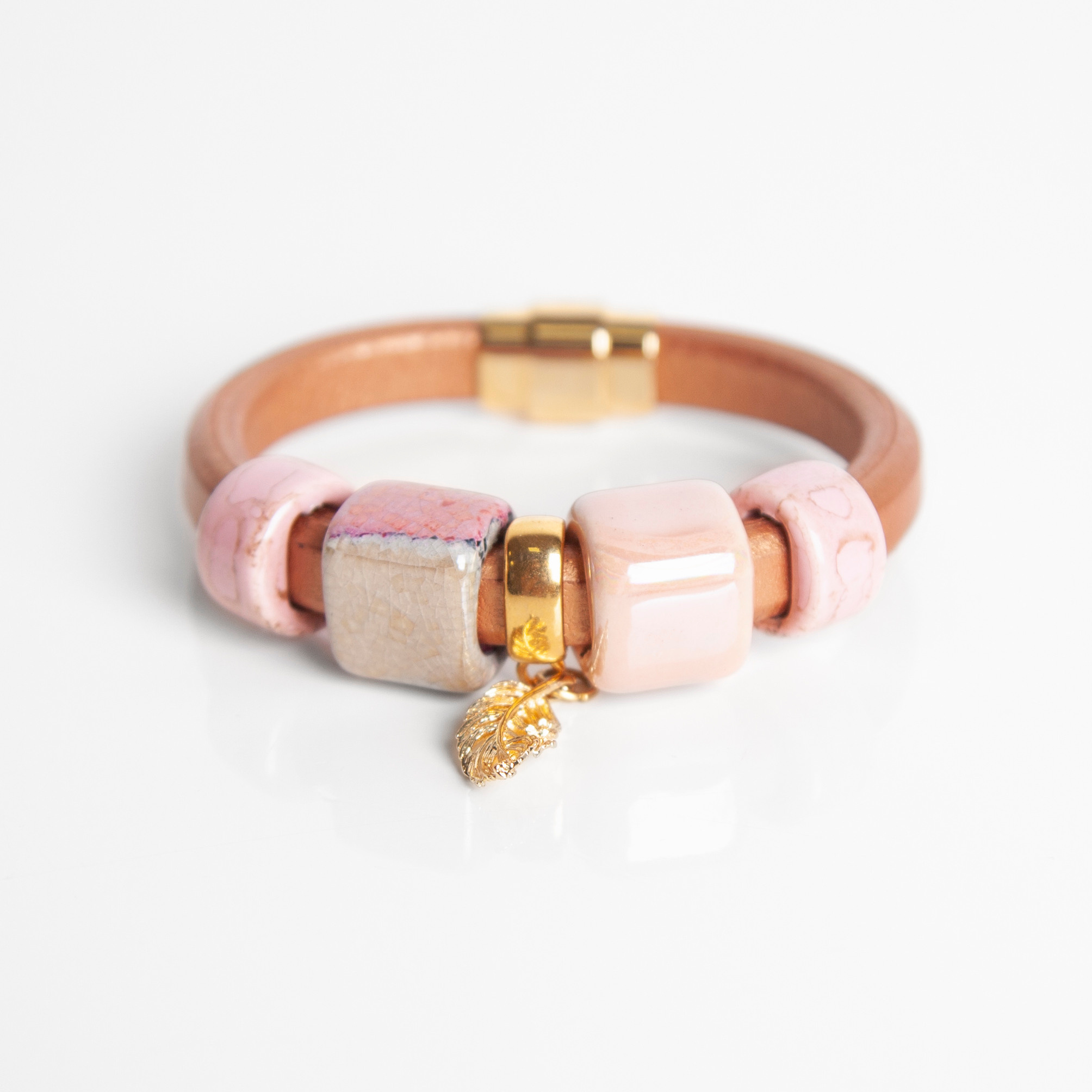 Розовый замшевый браслет с золотым пером посередине. 