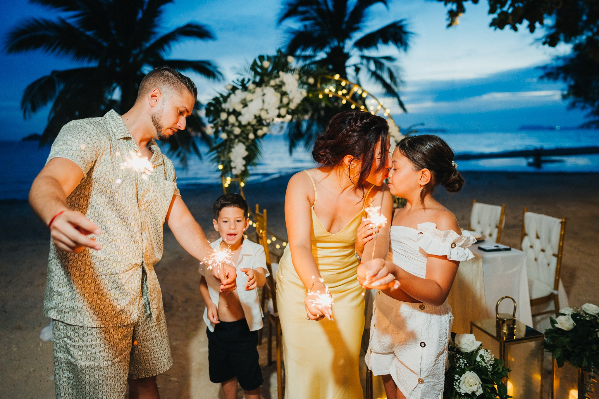 Bride and groom celebrating a beach wedding with their children in Koh Samui, Thailand, surrounded by tropical scenery and ocean views
