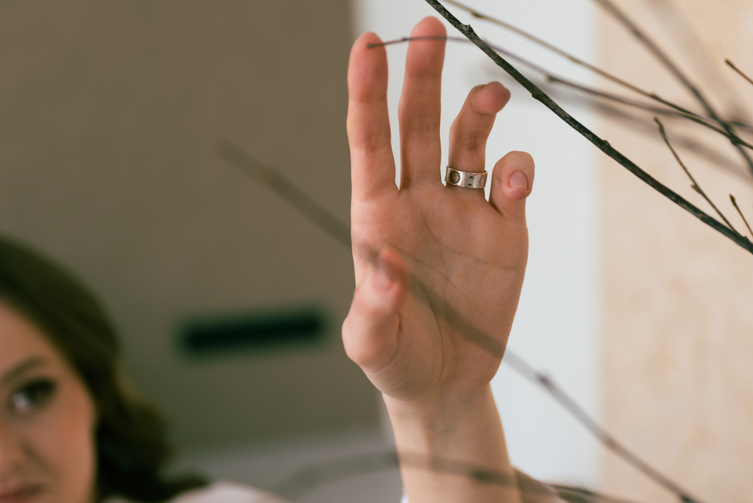 Фотостудия, на переднем плане ветви растения, женская рука осторожно касается веточки.