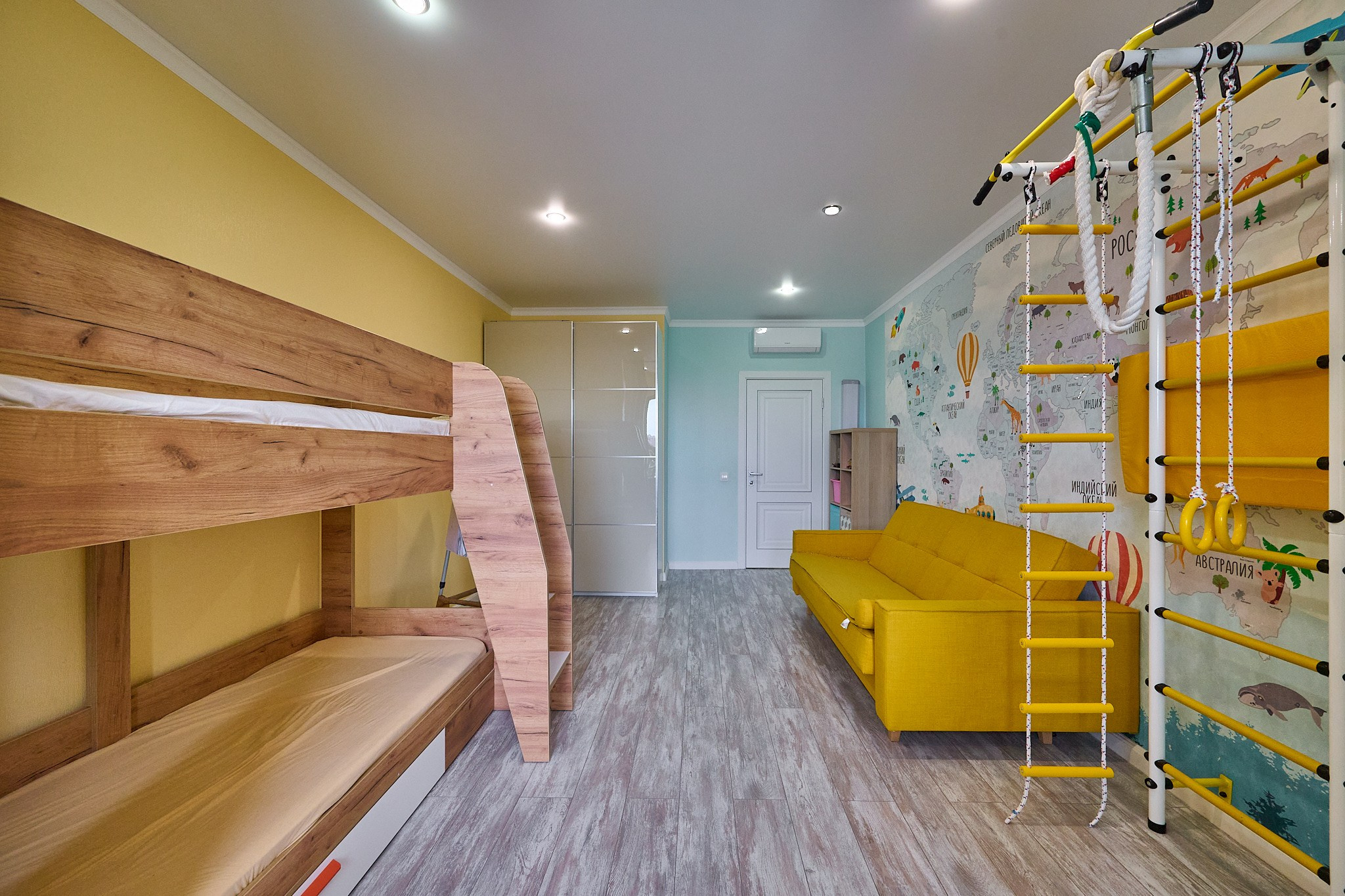 деревянная кровать место для занятий тренажёры желтые оттенки белая входная дверь 