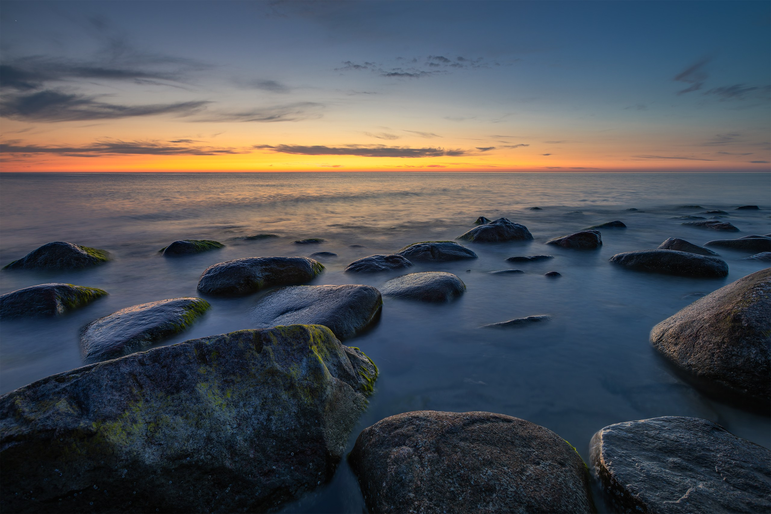 Beautiful midnight afterglow lighting the clouds and calm Baltic sea shore at Brüsterort.