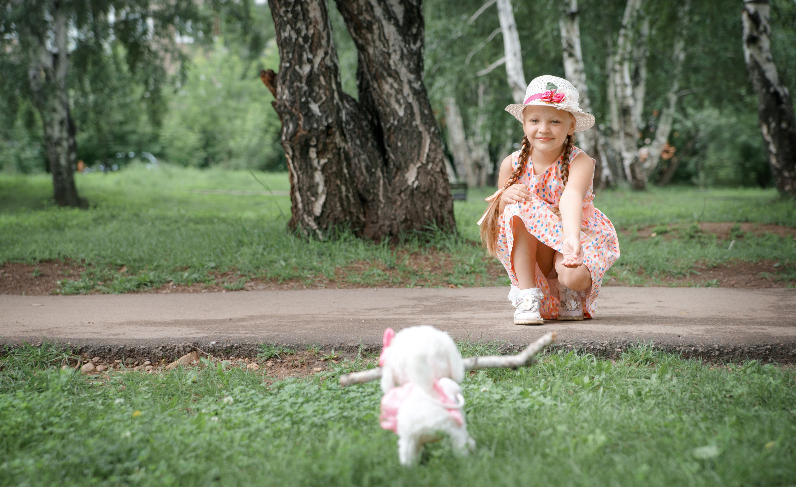 Детская фотосессия летом - щенок несет палочку девочке