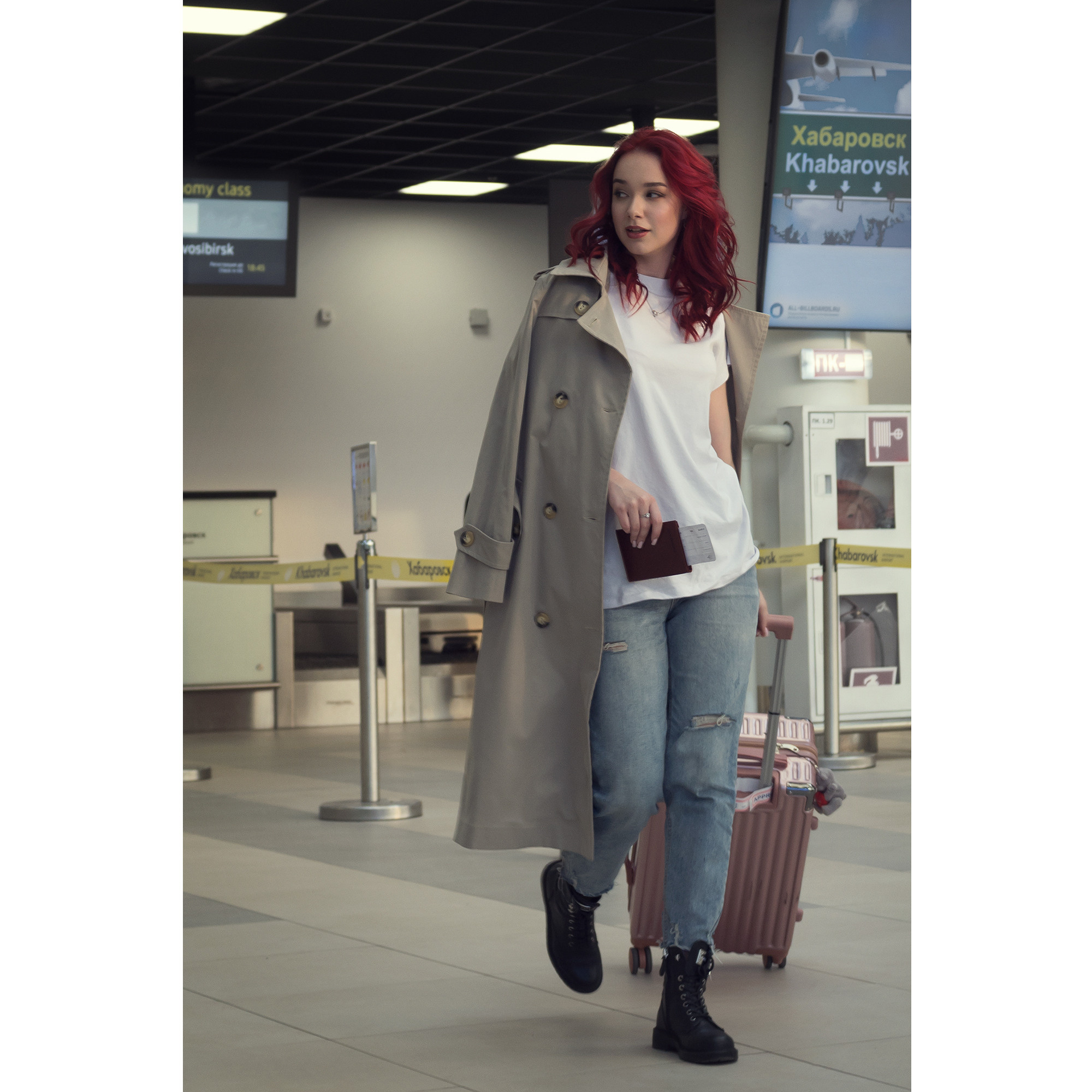 Девушка с чемоданом около стойки регистрации в аэропорту. Путешествие, вояж, перелёт в другой город или страну.