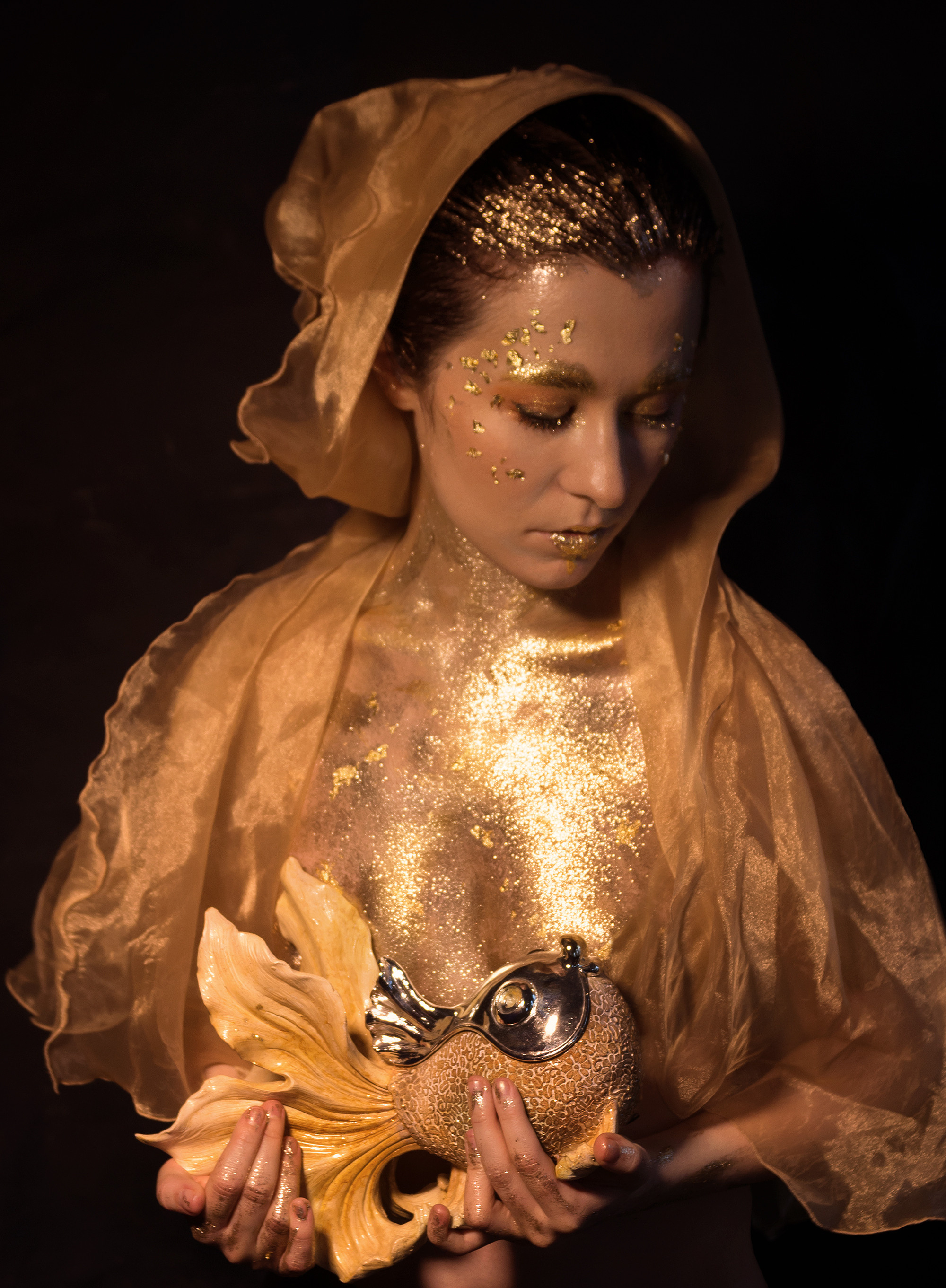 Девушка покрыта золотом, в руках золотая рыбка. Женский портрет, арт-проект.
