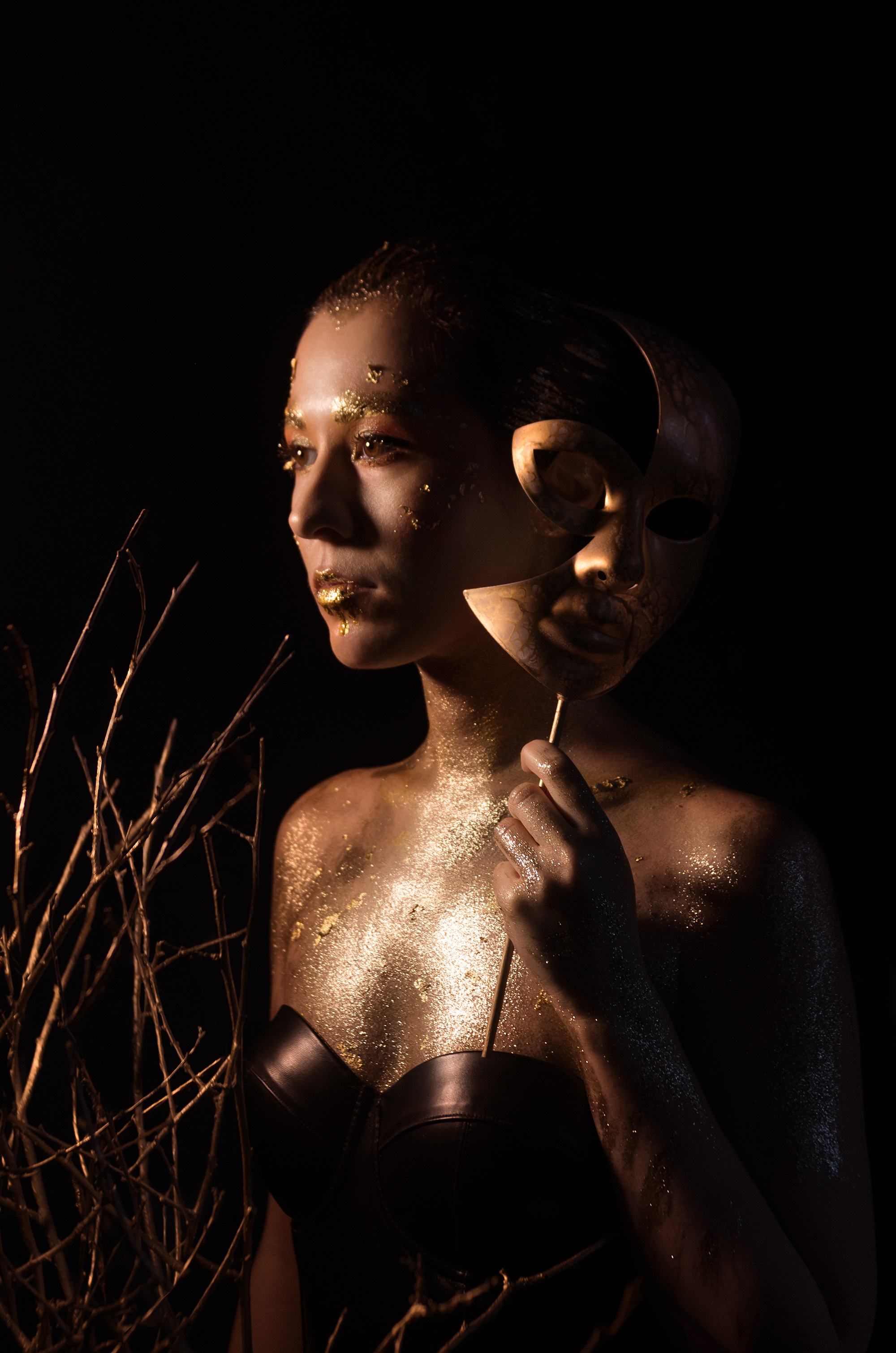 Девушка с золотой маской, боковое освещение, низкий ключ. Золотой макияж с поталью.