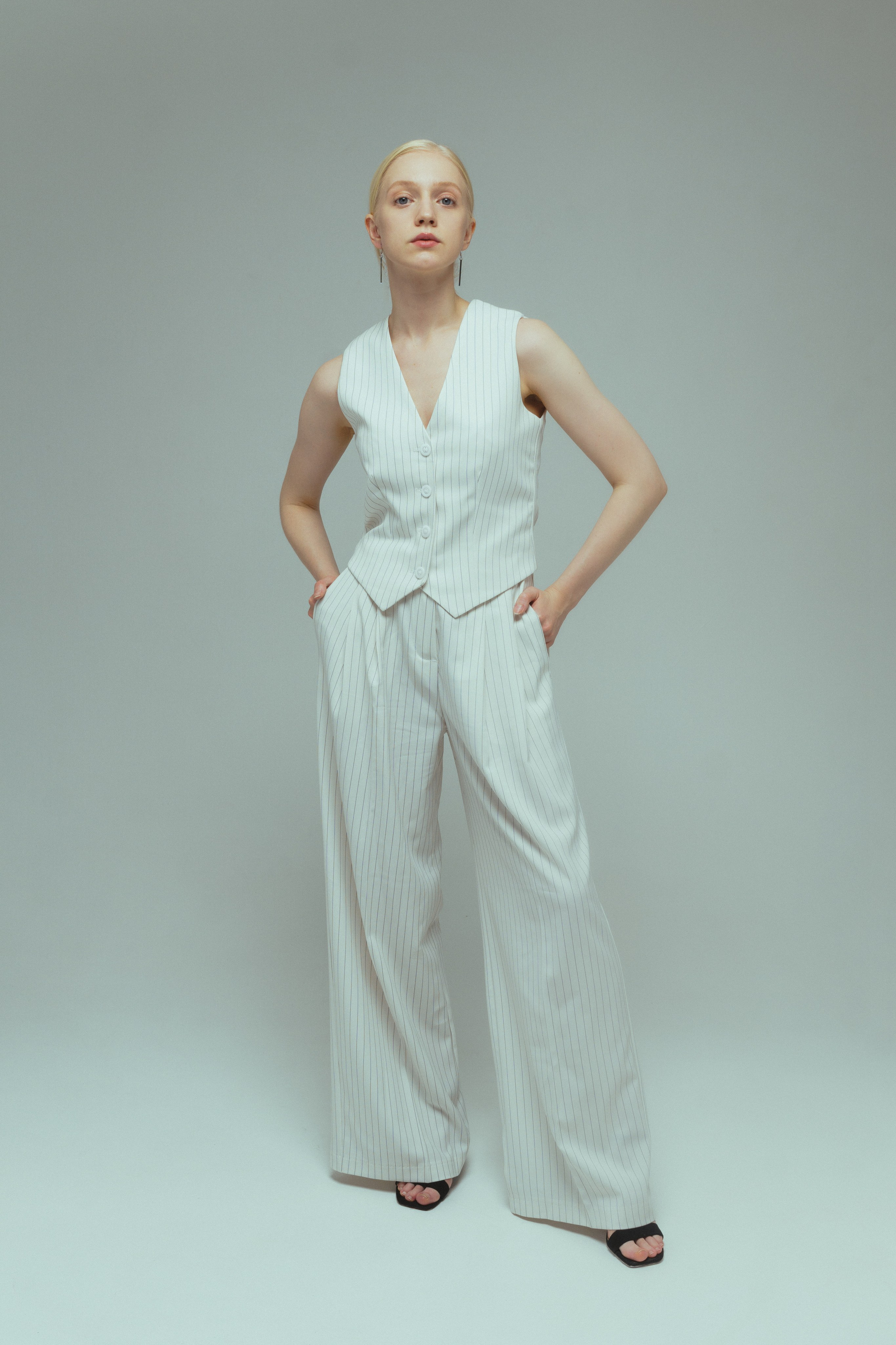 Девушка модель блондинка в белых брюках в полоску и жилете