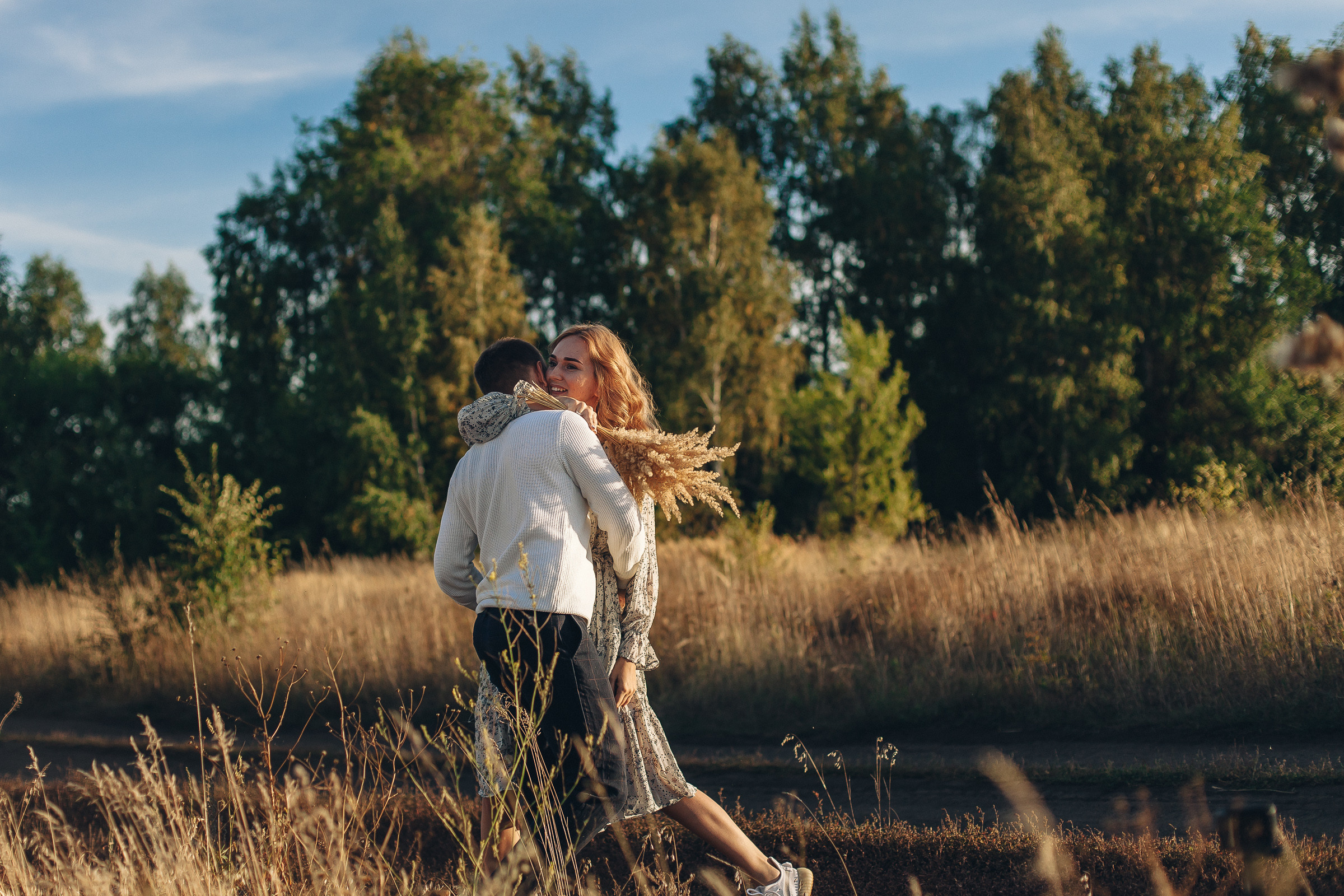Муж и жена бегают по поле и фотографируются