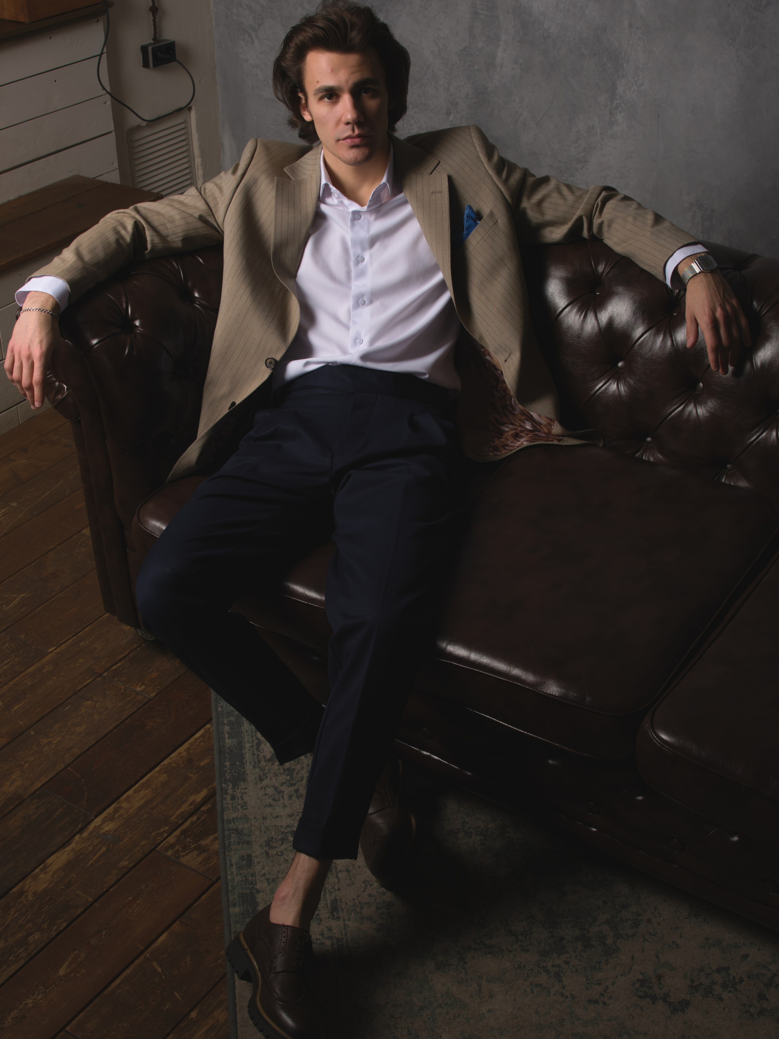 молодой джентельмен сидит на диване в расслабленной позе